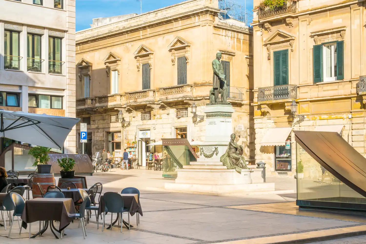 Outdoor restaurant tables set in a sunlit historic square in Lecce.