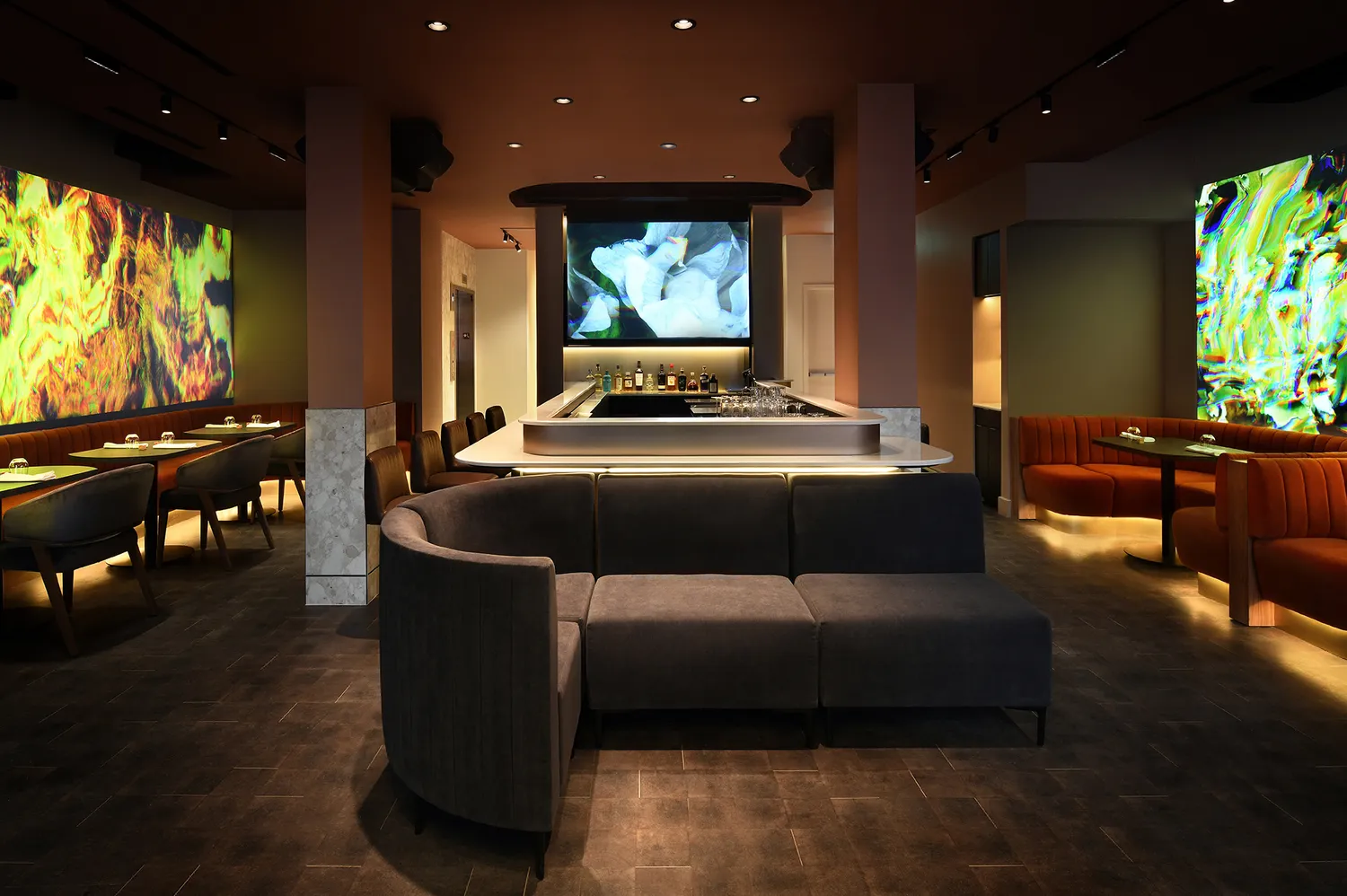 Modern hotel lobby bar lounge with circular seating and illuminated wall displays.