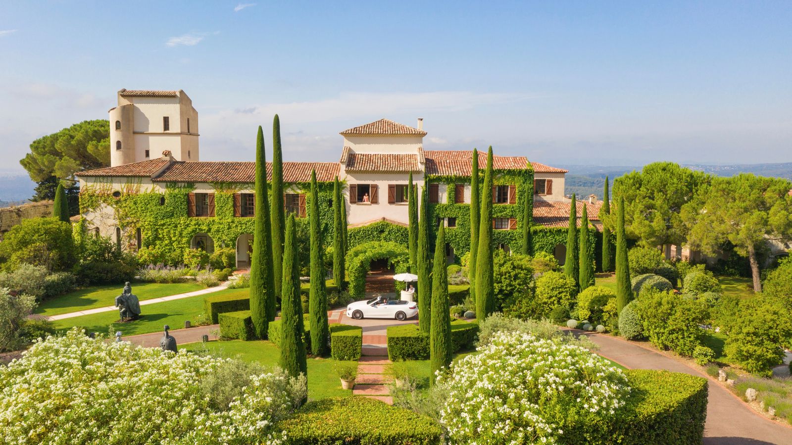 Exterior view of a majestic white villa-style Palace hotel surrounded by traditional gardens.