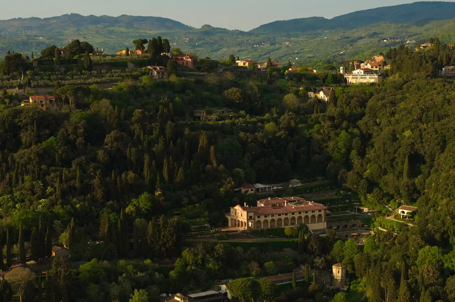 Aerial view of Villa San Michele surrounded by lush Tuscan greenery and rolling hills.