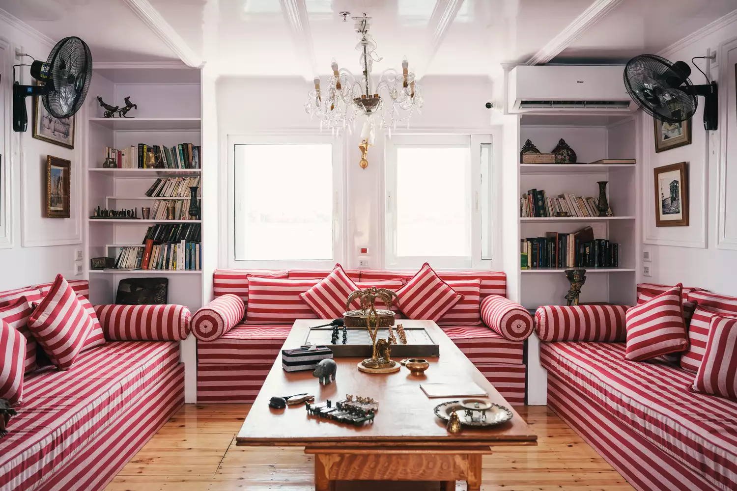 Interior of a lounge area on a boat featuring red and white striped sofas and artisanal Egyptian decor.