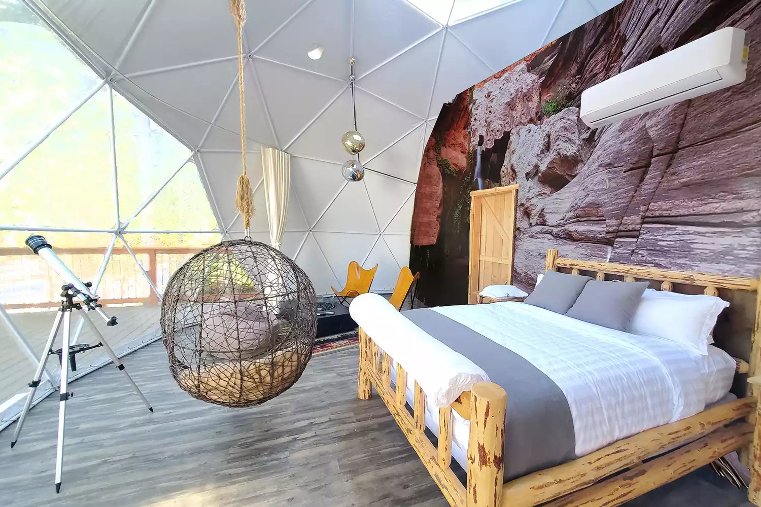 Interior view of a Clear Sky Resort dome showing a luxury bed, seating area, and stylish modern decor.