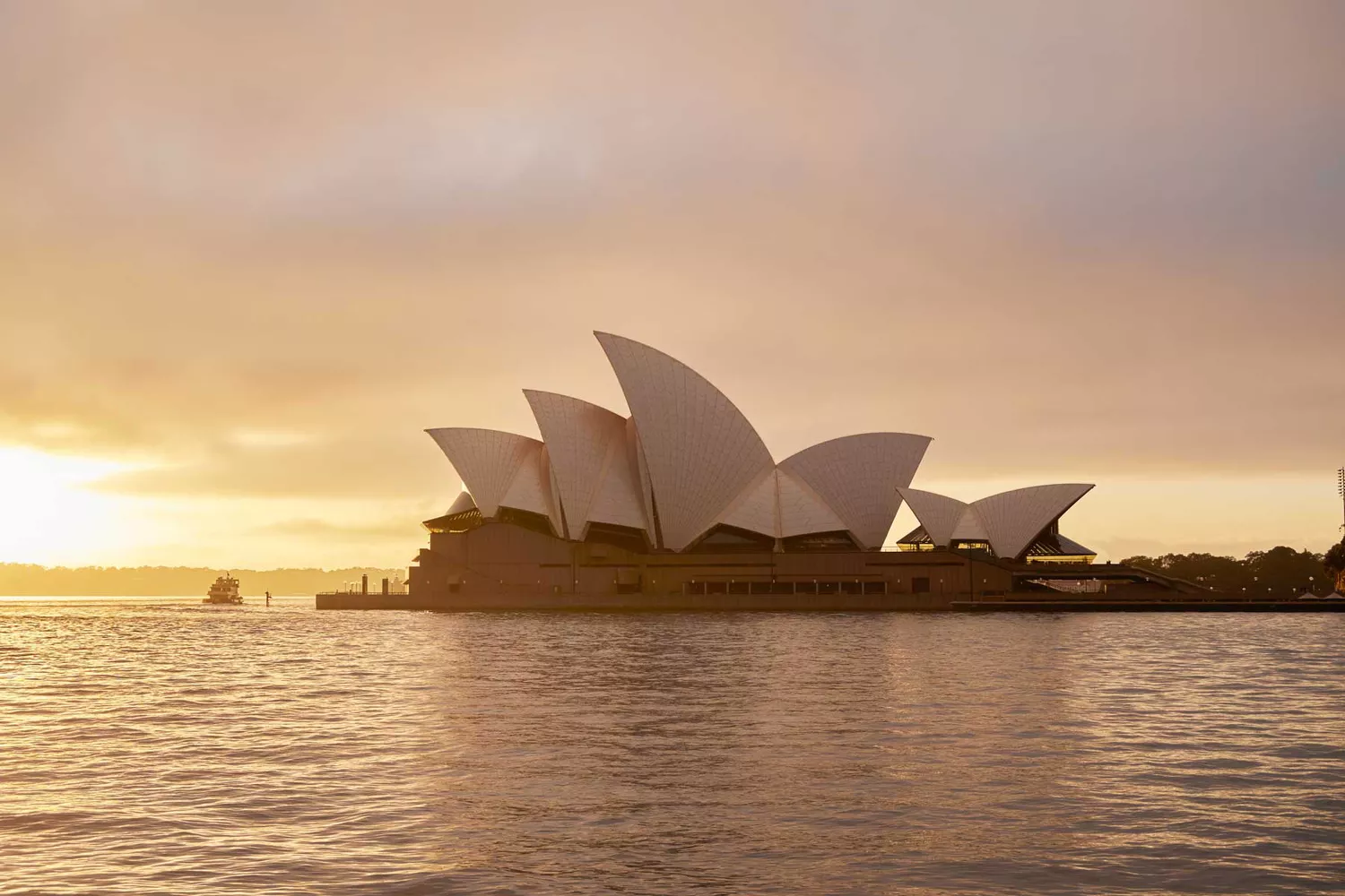 The Sydney Opera House at sunset with harbor views.