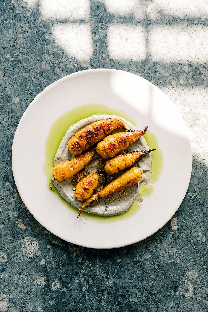 A close-up of a vibrant and artistically arranged modern Colombian dish on a ceramic plate.