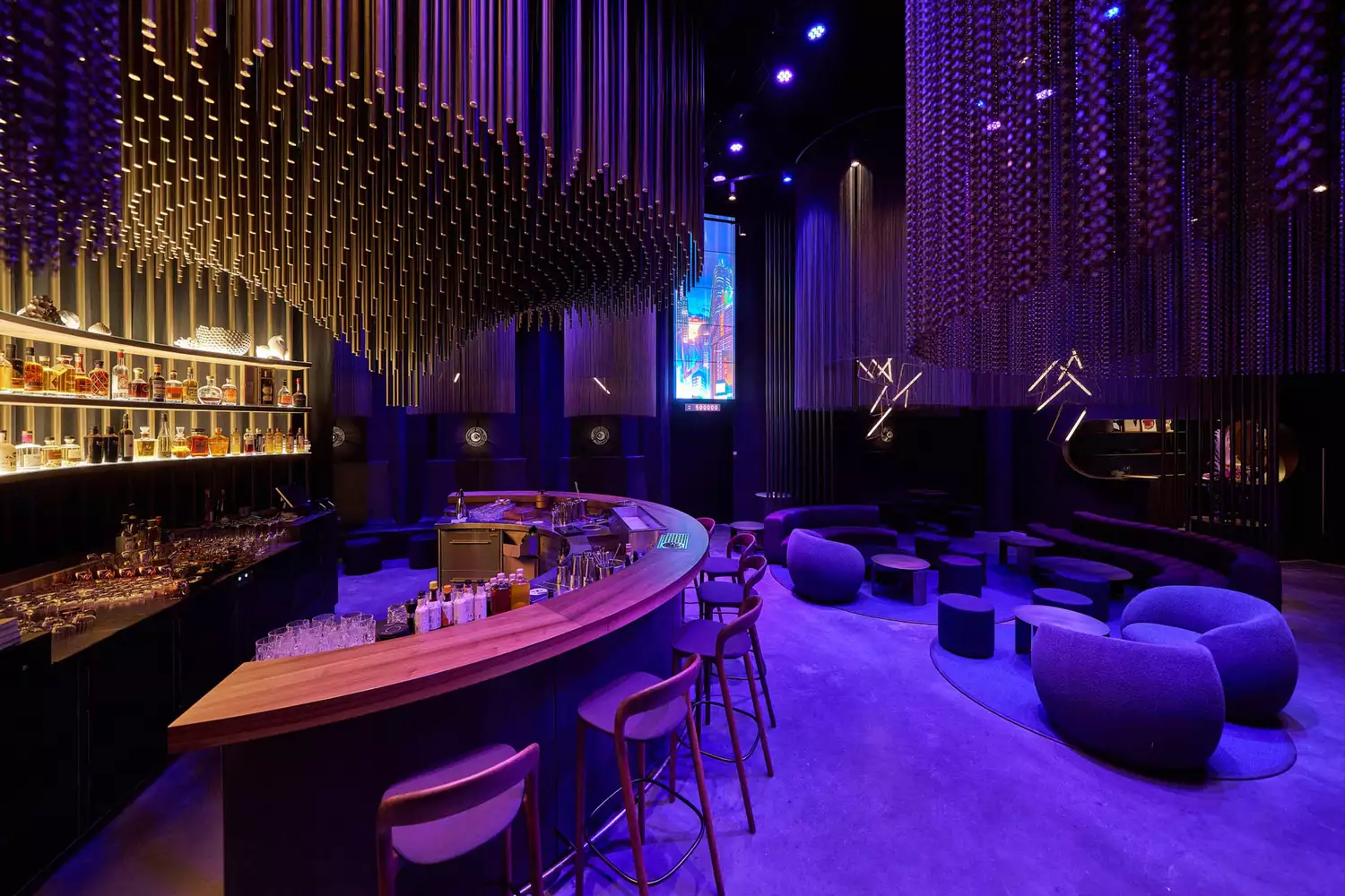 A luxury bar at Eatrenalin featuring vibrant purple neon lighting and modern decor.