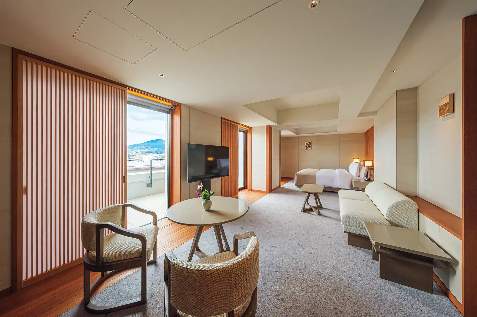 Luxury hotel suite with modern furnishings and a view of the mountains through sliding doors.
