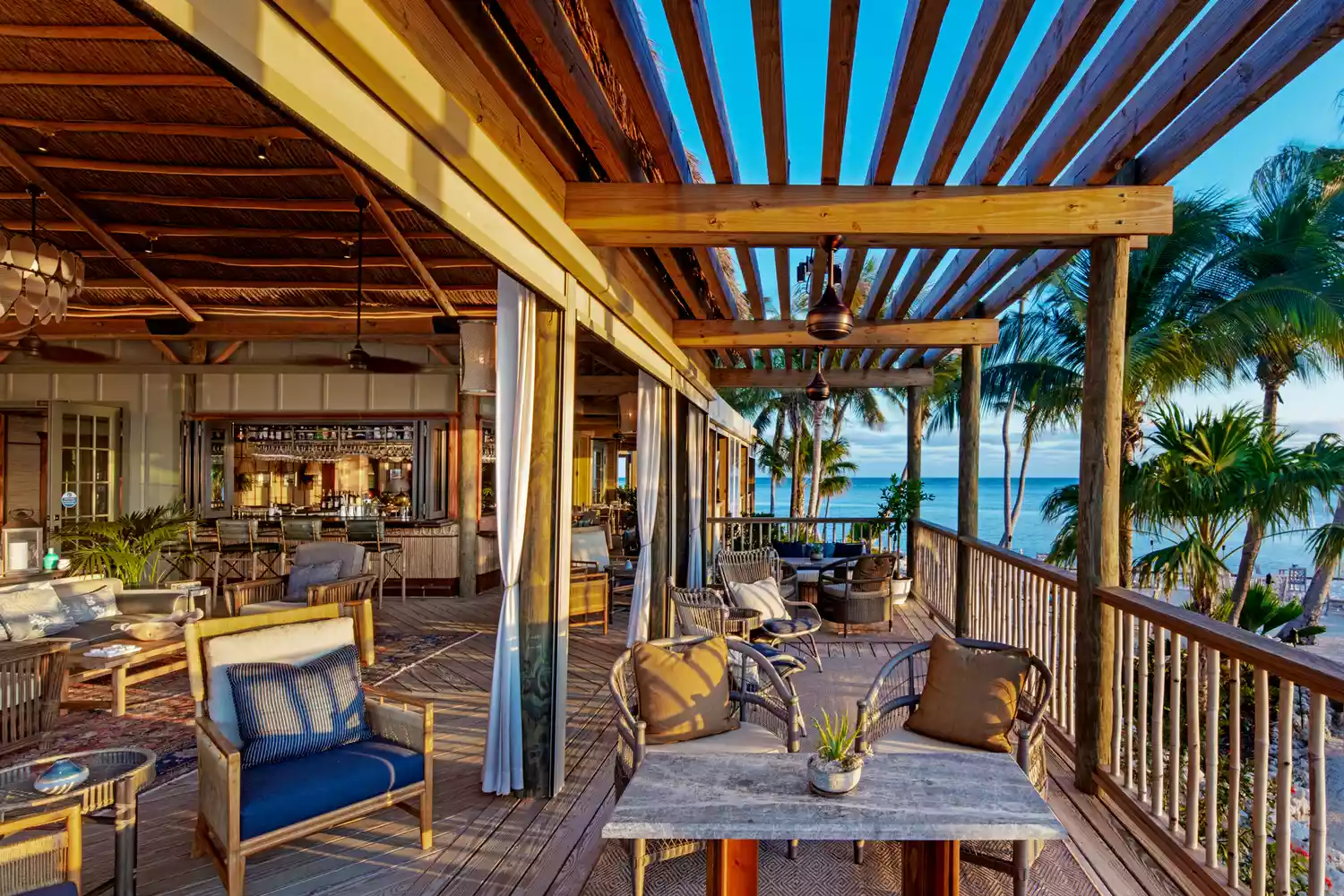 The upscale, tropical interior of a thatched-roof bungalow showing high-end furniture and no electronic distractions.