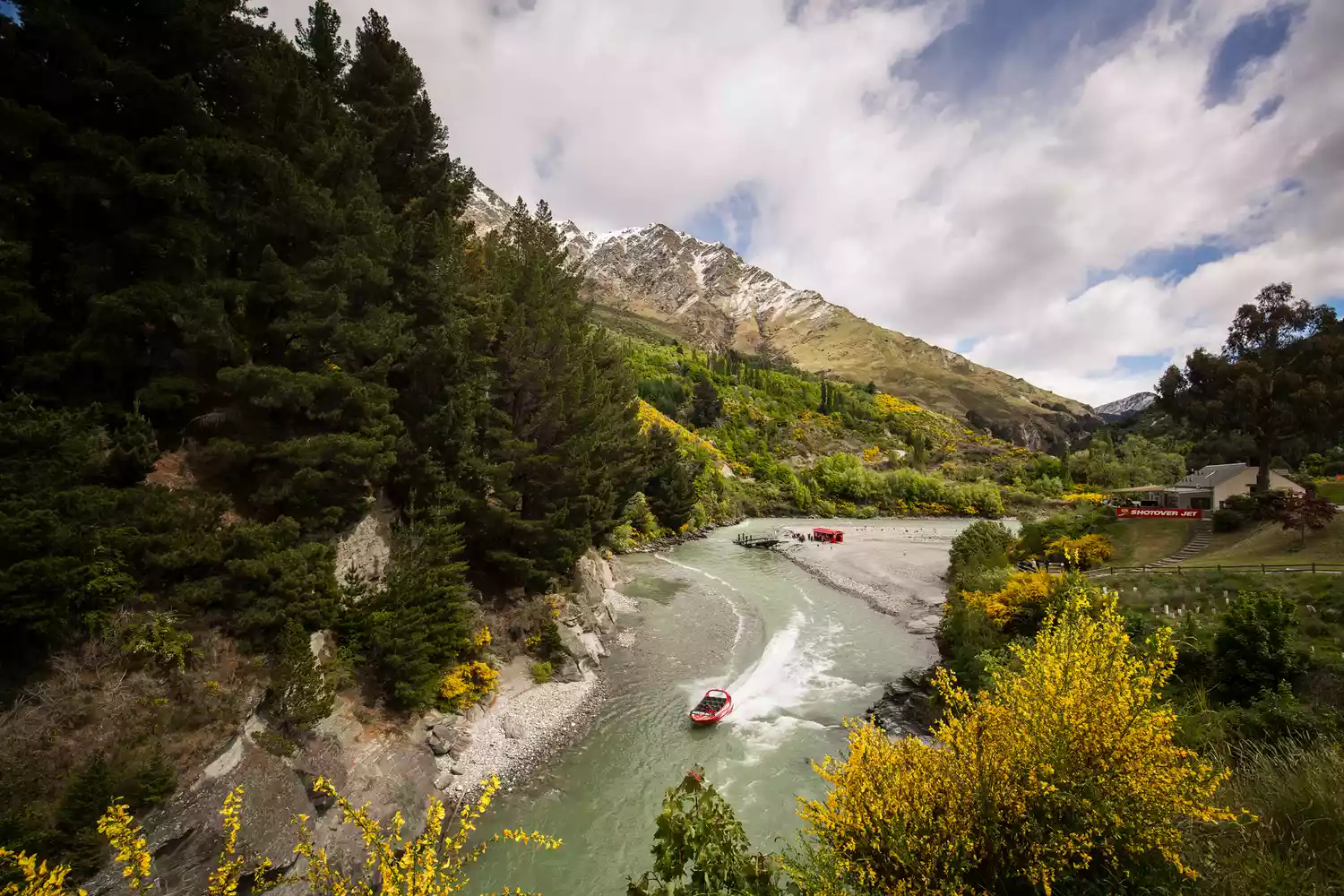 A yellow jet boat speeding through the narrow canyons of the Shotover River