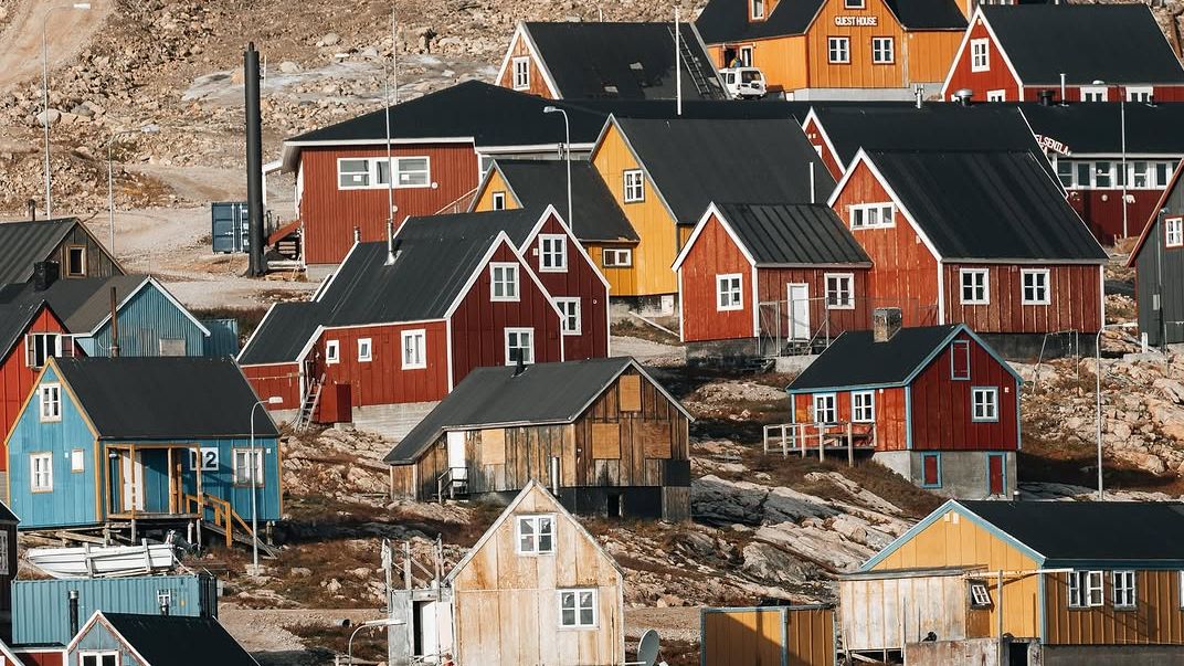 A scenic wide shot of the Greenlandic coastline showing the scale of the Arctic landscape.