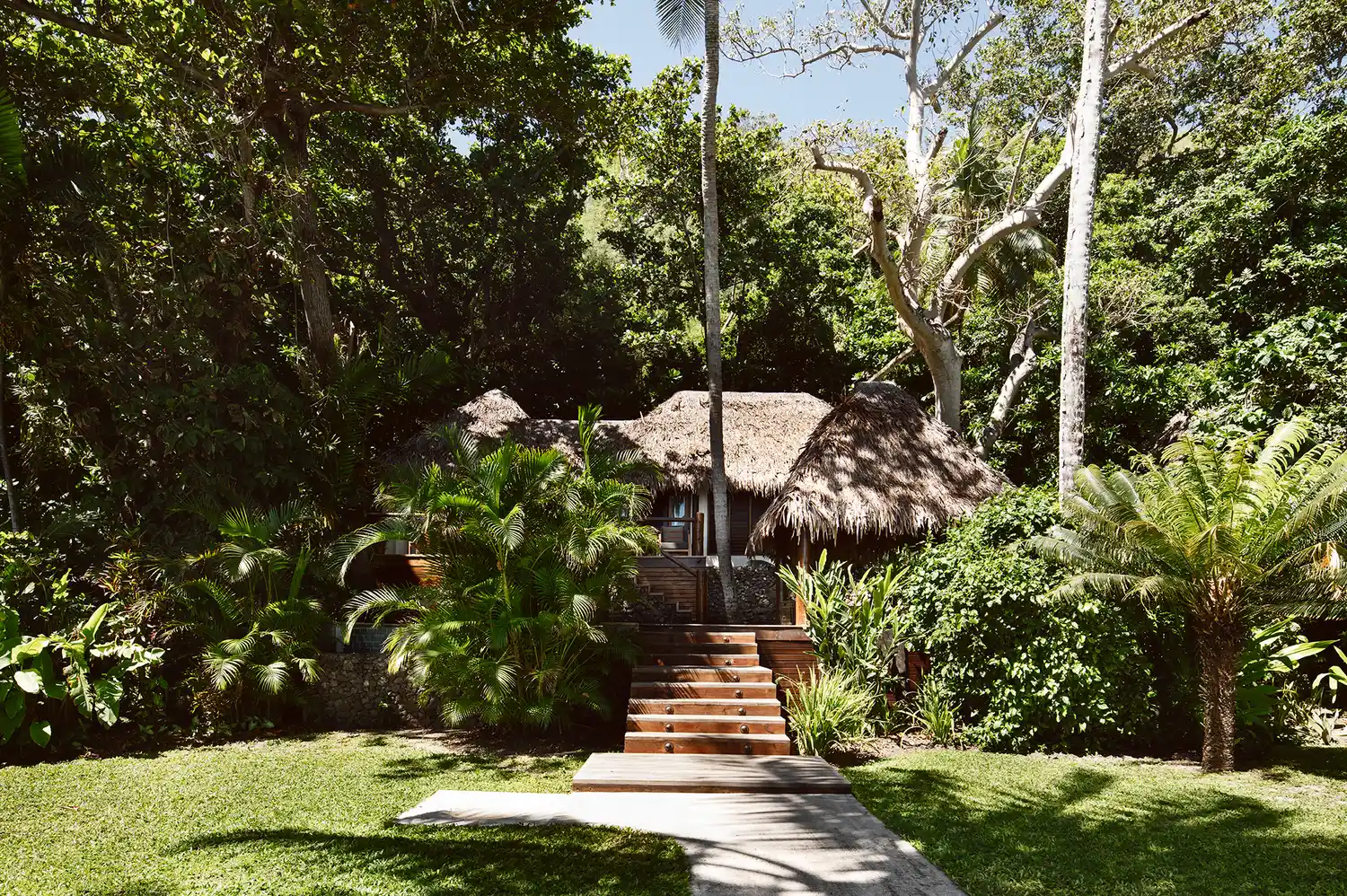 A luxury thatched-roof pool villa at Tokoriki Island Resort surrounded by manicured tropical gardens.