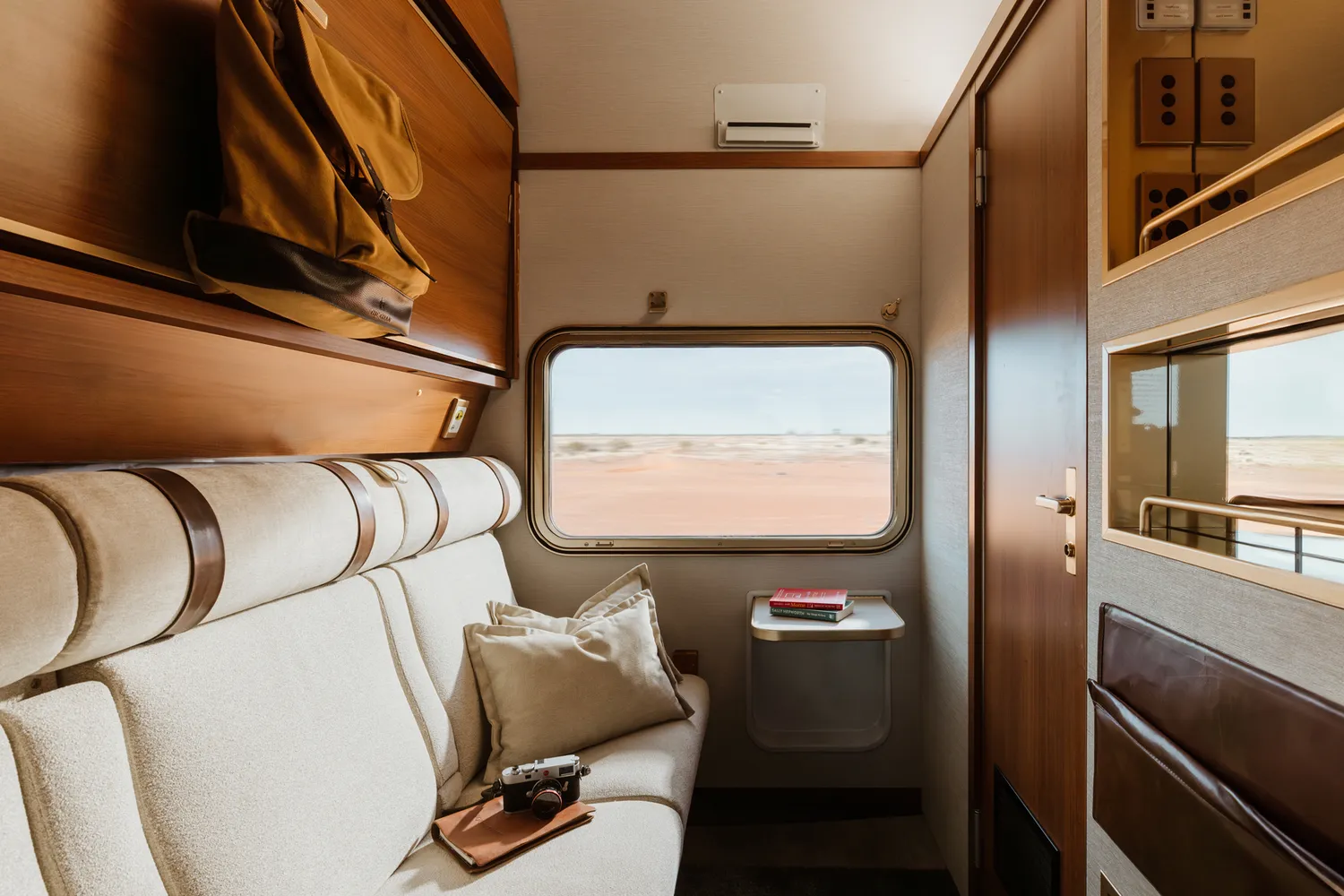 Interior of a modern train cabin with a window overlooking an arid landscape.