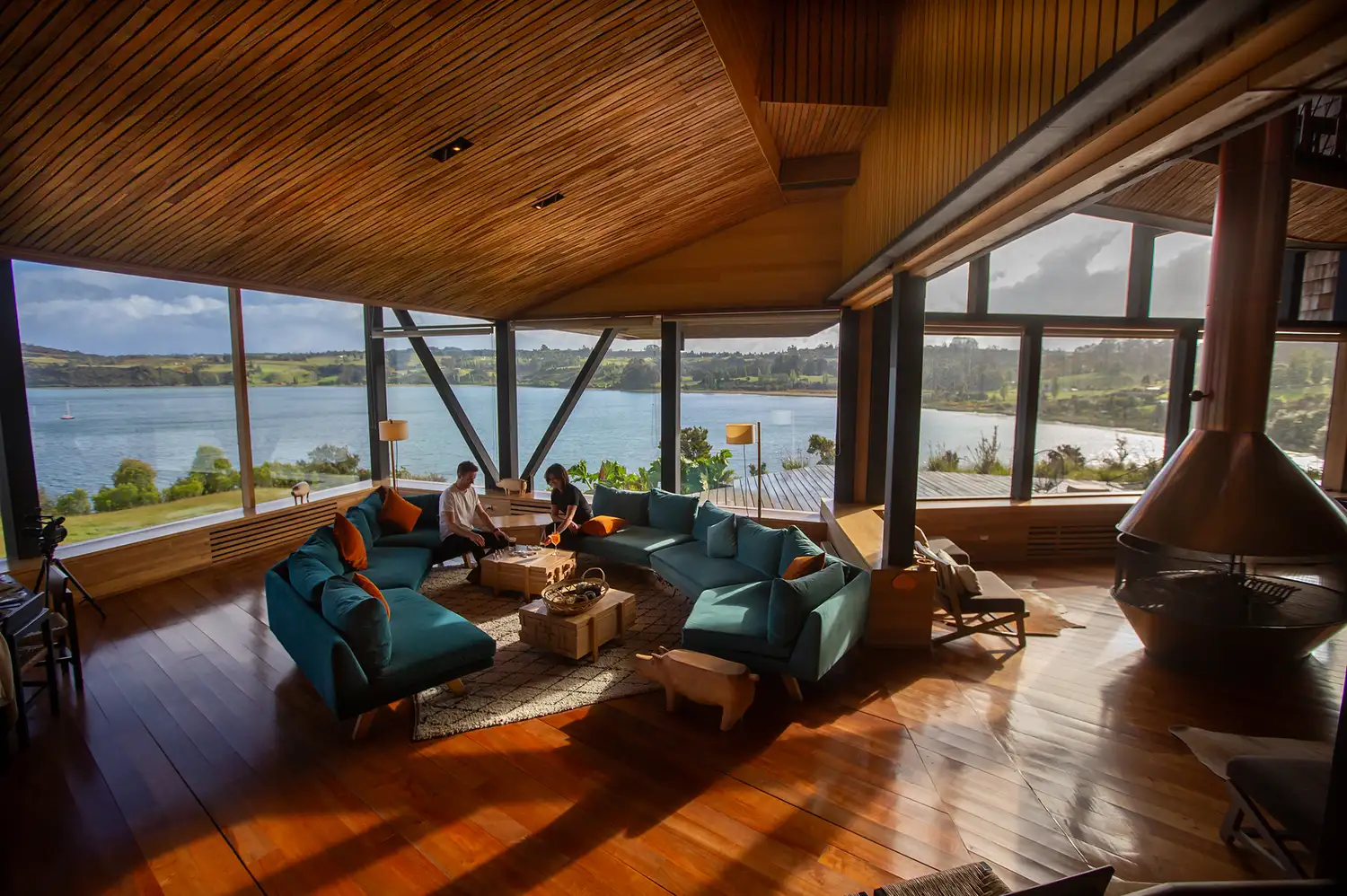 Interiors of a modern hotel lounge with a fireplace, comfortable seating, and wide panoramic windows showing the river.