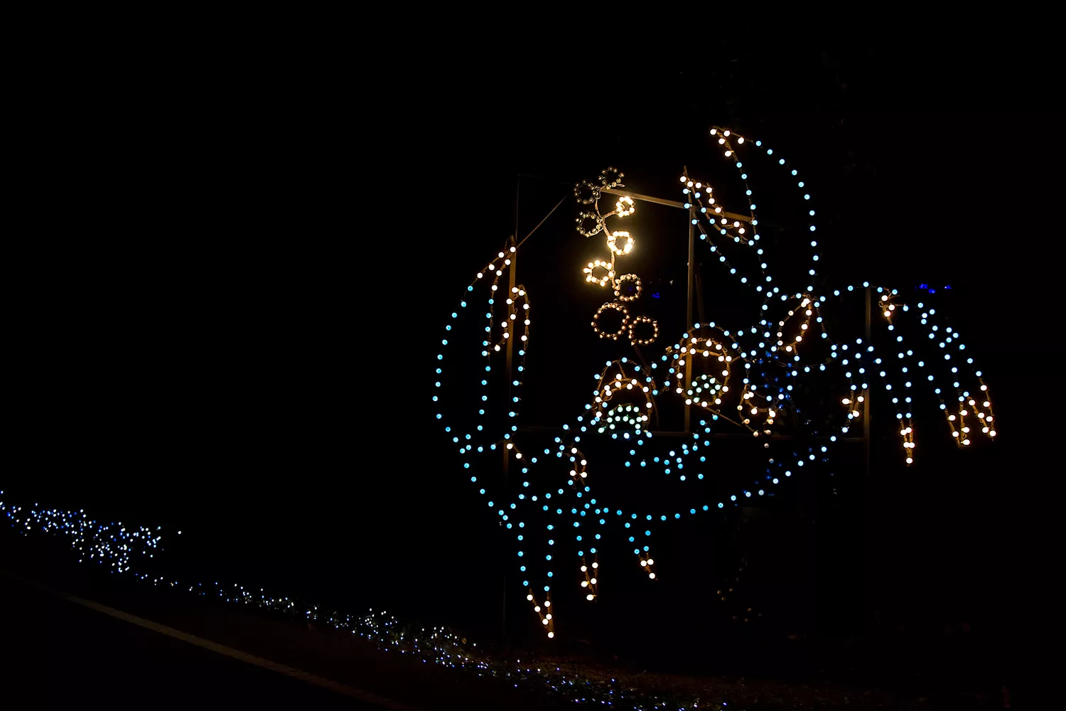 A large holiday light display shaped like a blue crab in the night sky.