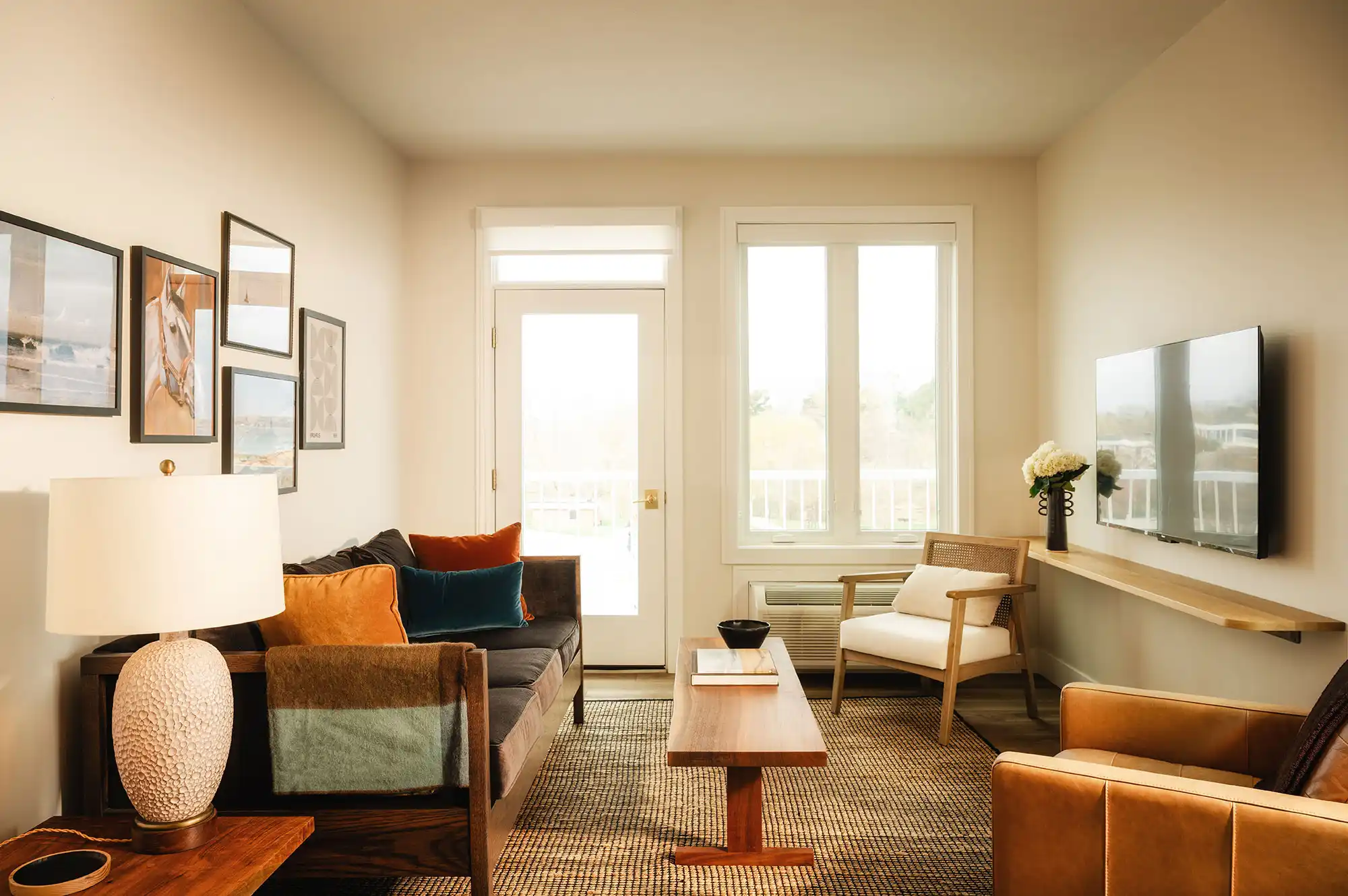 A spacious hotel suite living area with modern seating and a wall-mounted television.