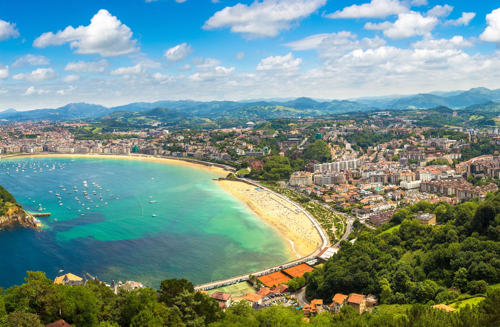 Historic coastal buildings overlooking a calm bay beach in San Sebastián.