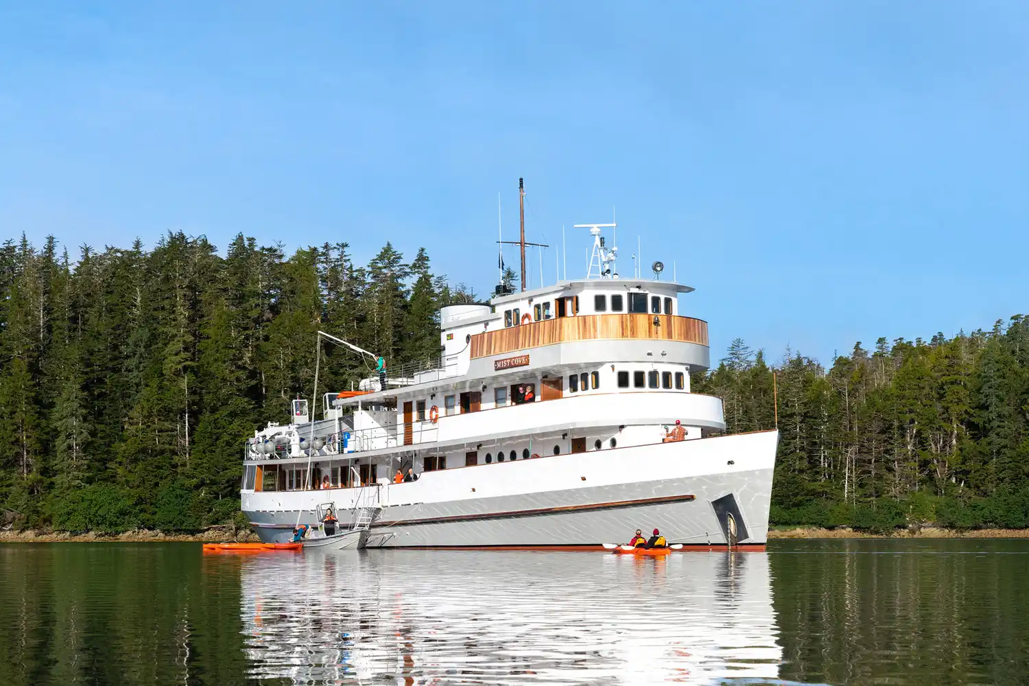 The Mist Cove vessel anchored near a densely forested Alaskan shoreline.