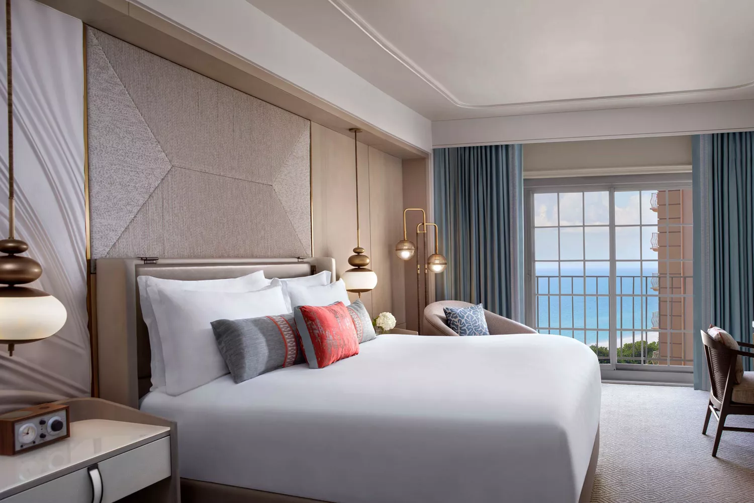 An elegantly appointed bedroom in a king suite with ocean views and light coastal decor.