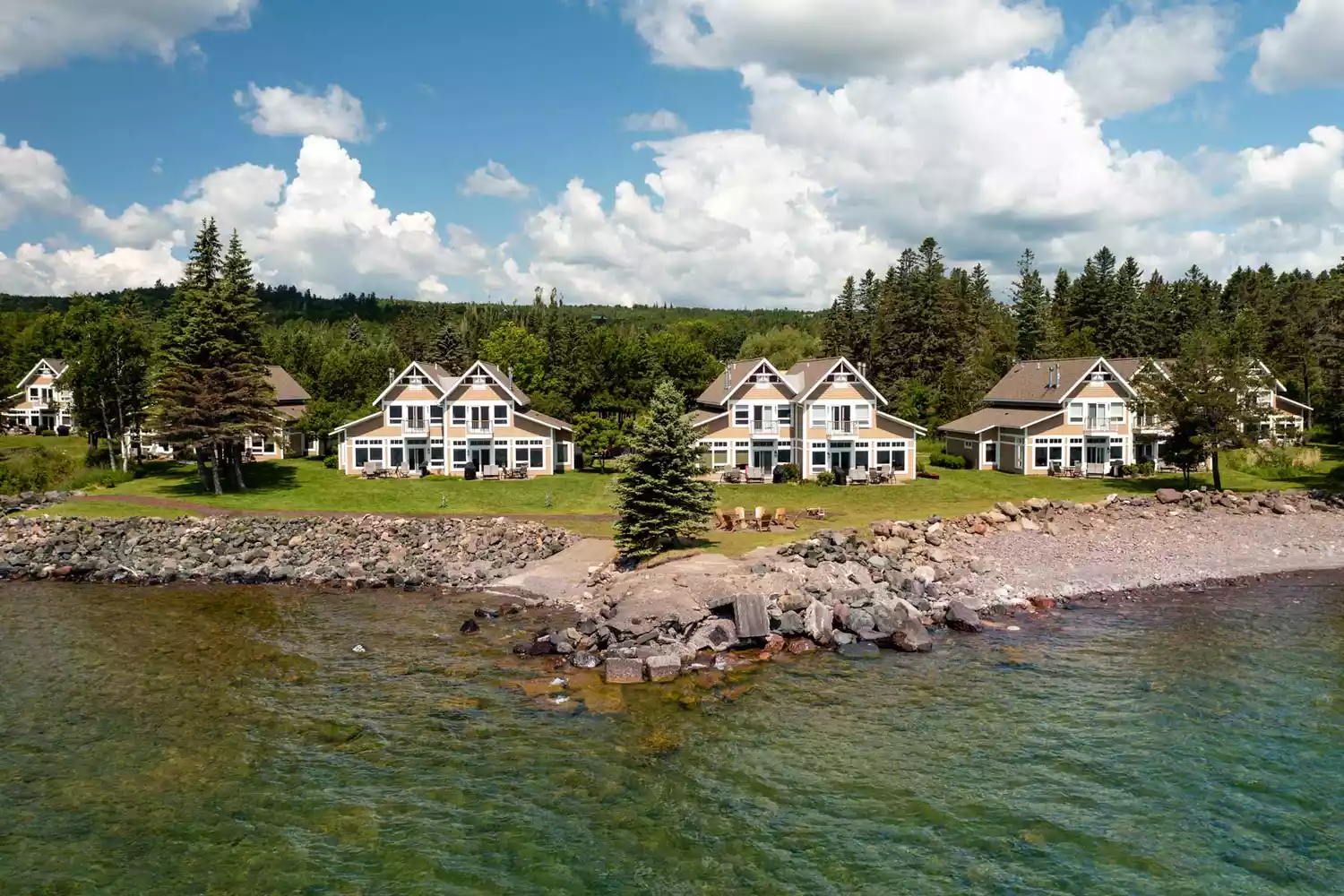 Larsmont Cottages nestled among trees along the rocky shoreline of Lake Superior.