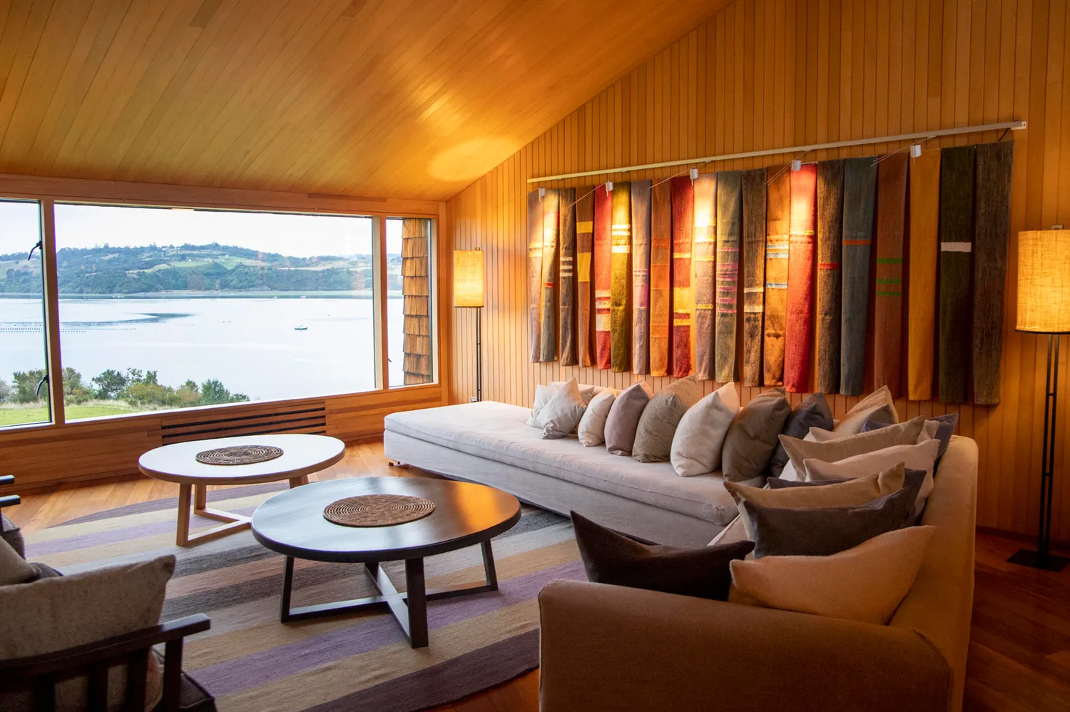 A hotel sitting room featuring natural wood finishes and a large traditional woven textile hanging on the wall.