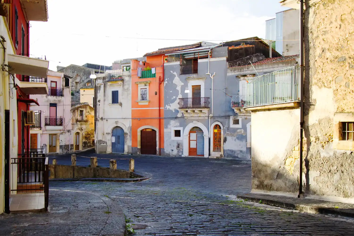 Colorful rustic buildings lining a quiet cobblestone street in Militello.