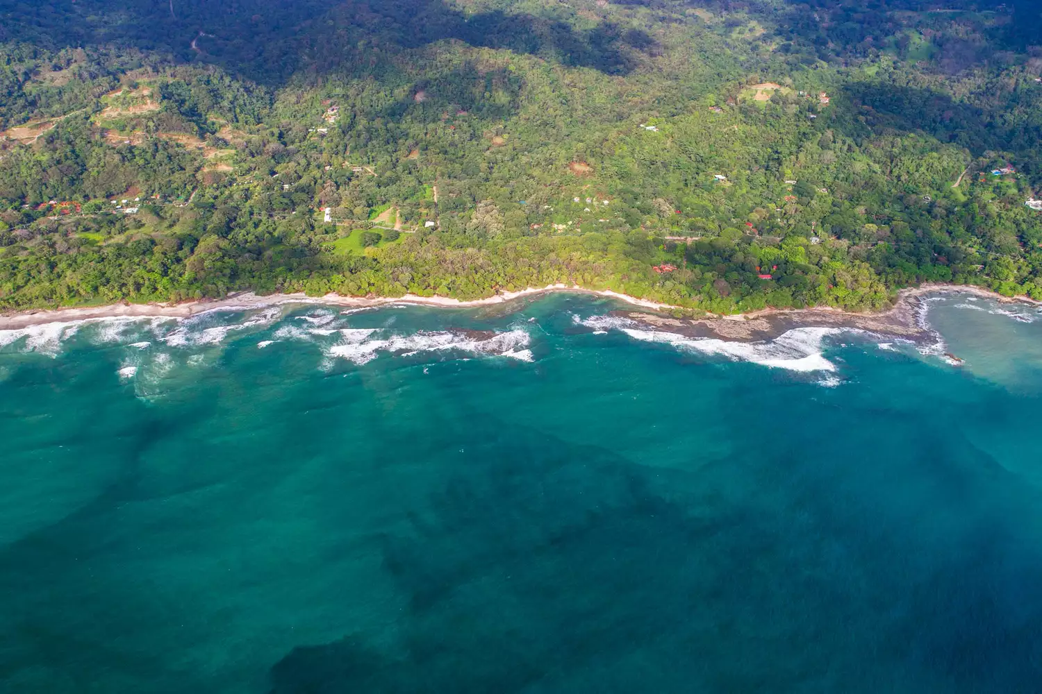 Aerial view of the lush green coastline and blue waters of the Nicoya Peninsula in Costa Rica.