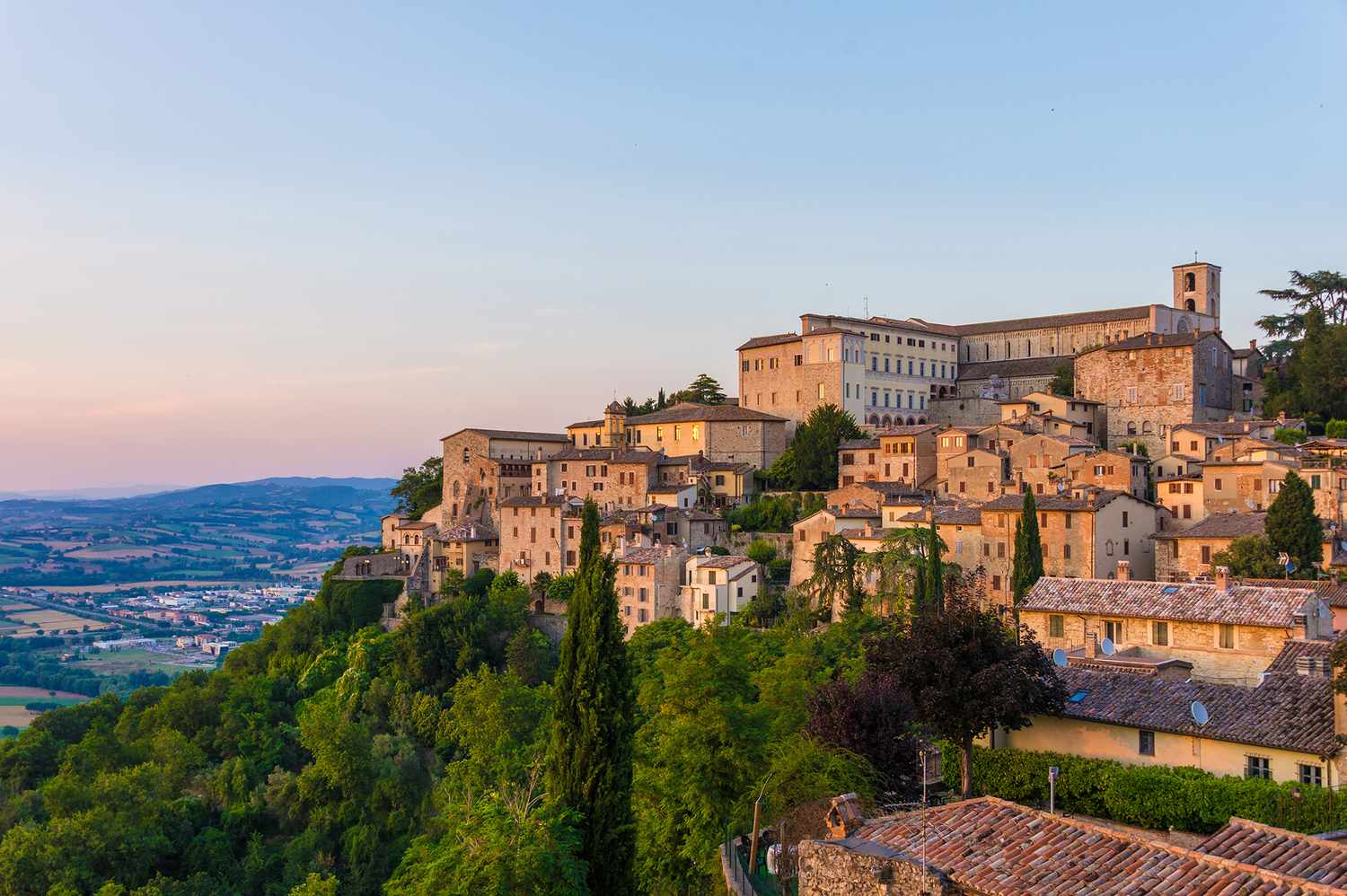 A tranquil view of Lake Trasimeno at dusk with distant mountains.