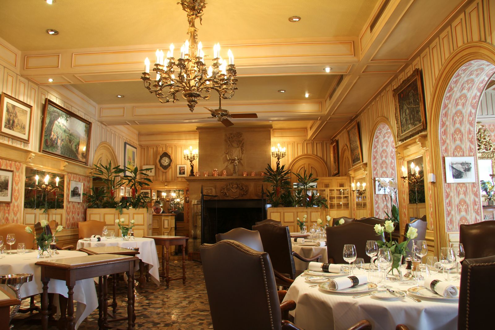 An elegant dining room featuring a grand chandelier and neatly set tables for fine dining.