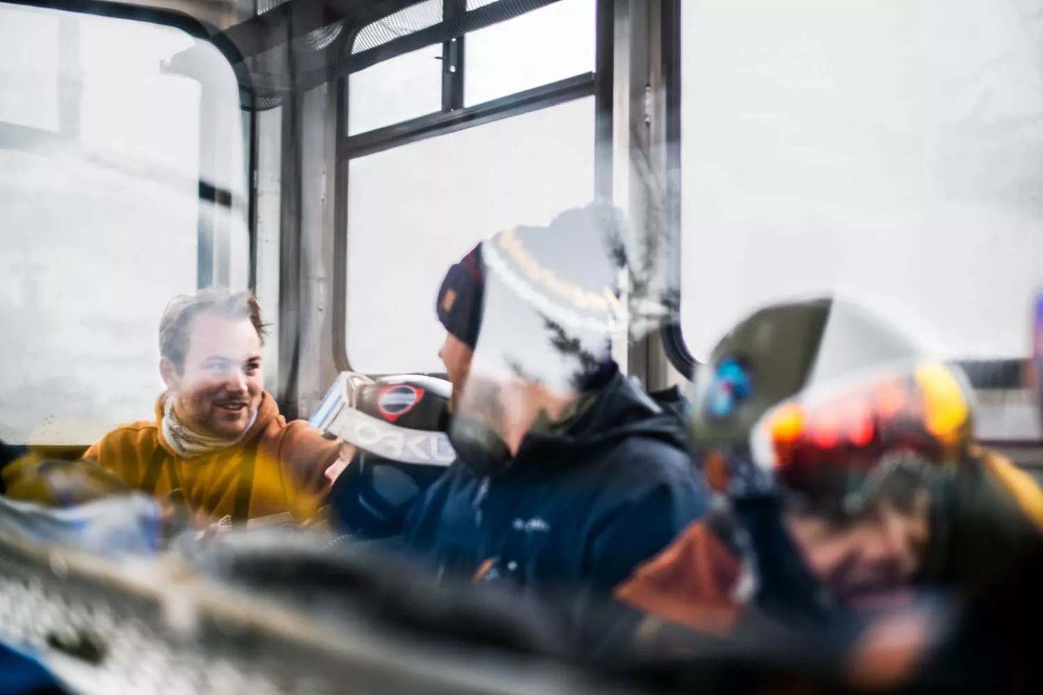 Four men sitting inside the cabin of a snowcat during a ski trip.