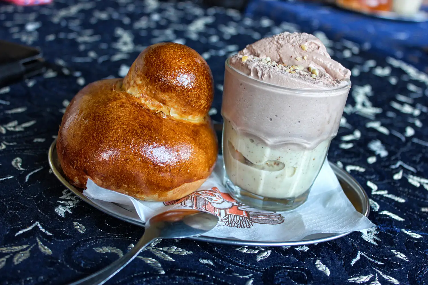 A close up of a traditional Sicilian brioche col tuppo served with granita and cream.