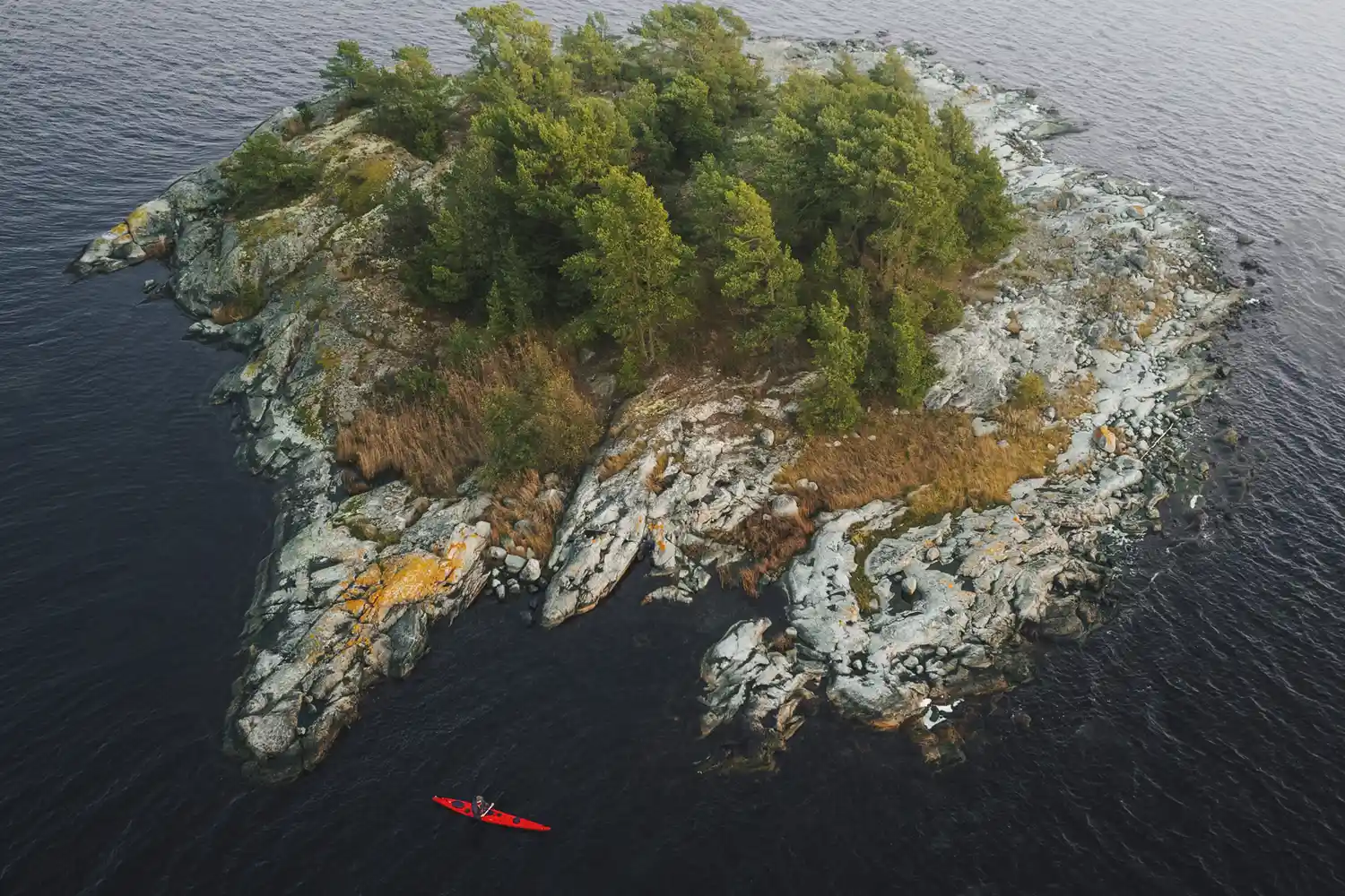Aerial view of a kayaker near a forested islet in a Swedish national park.