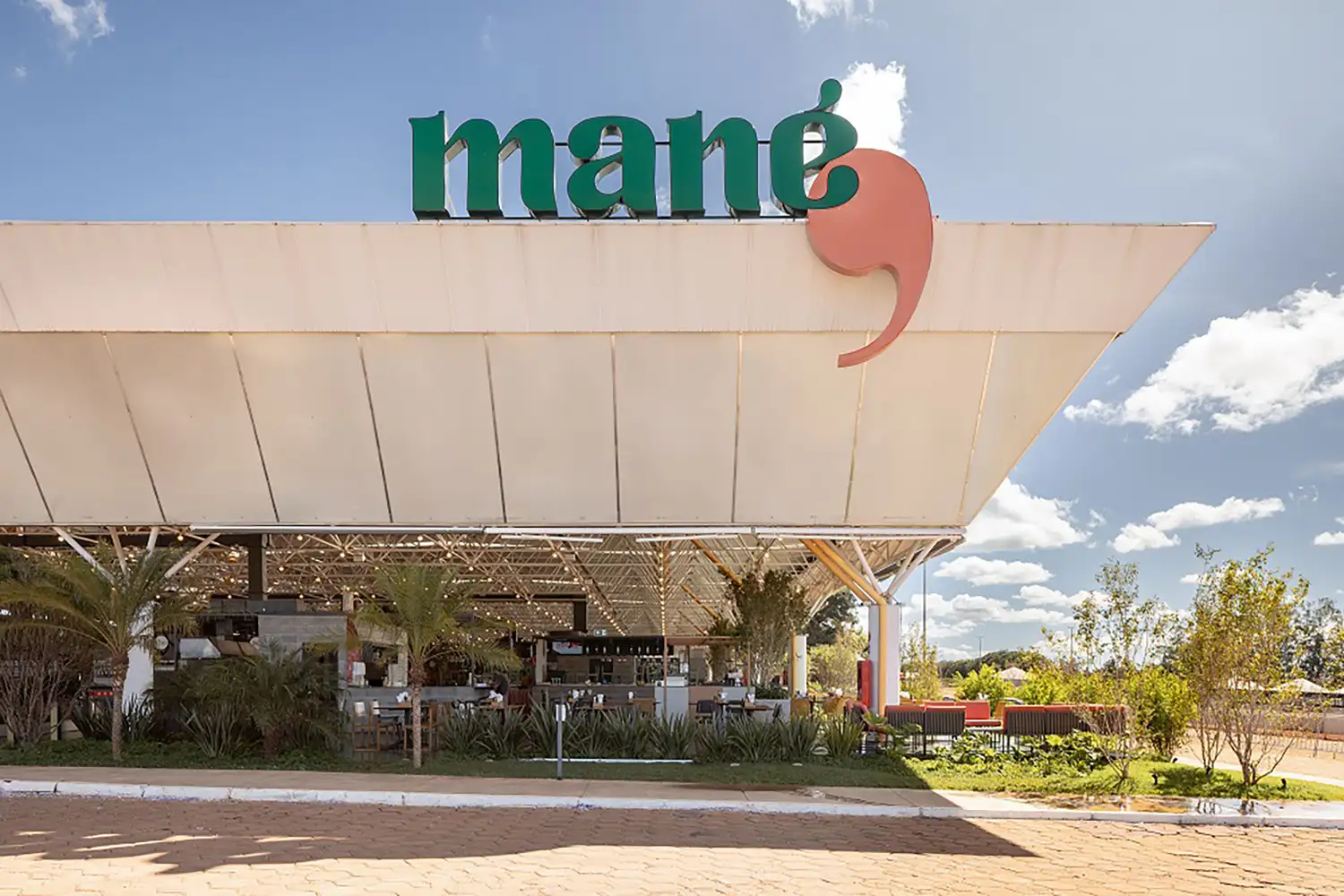 Modern entrance of Mané Mercado featuring contemporary architecture and plants.