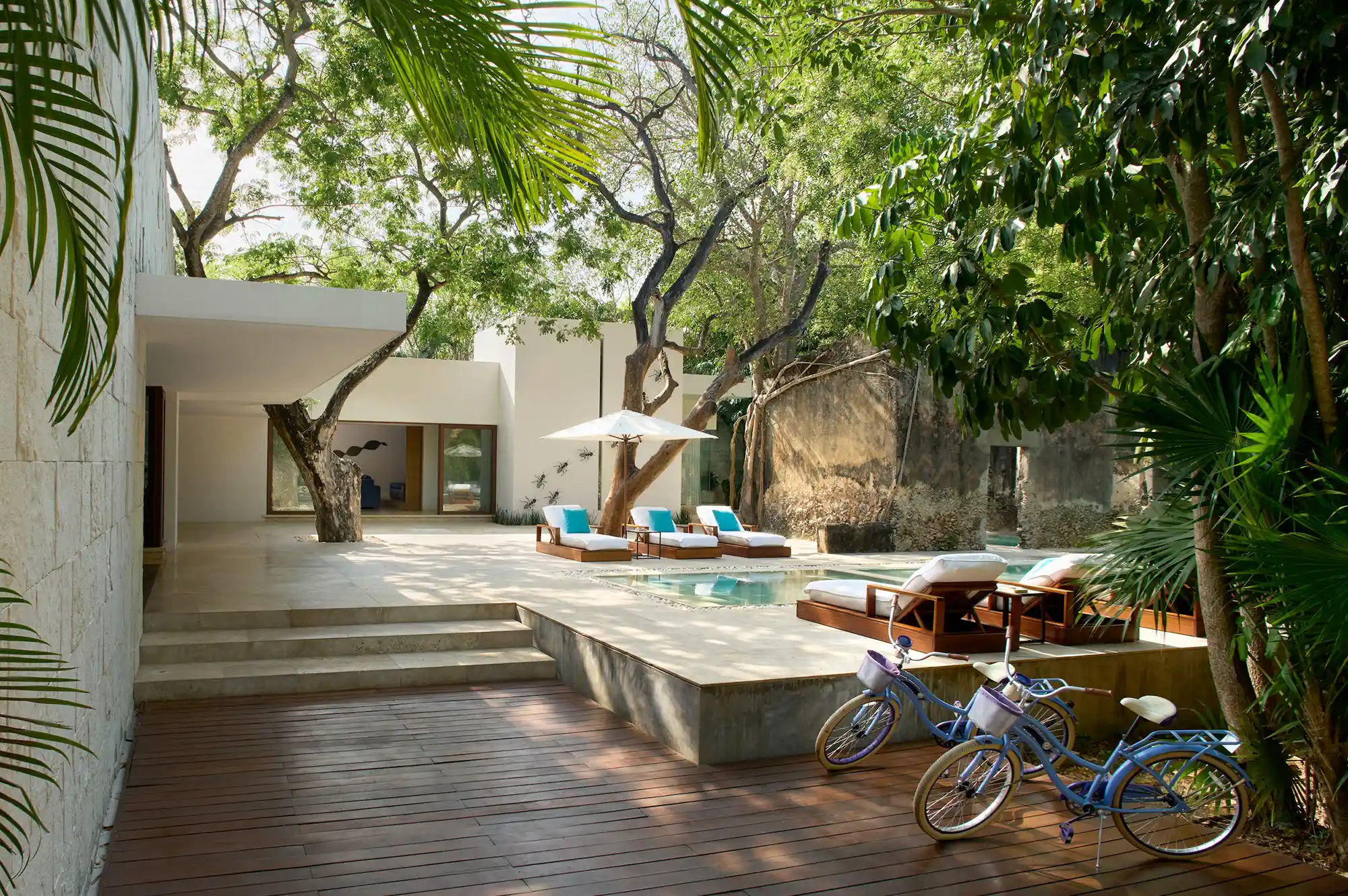 A peaceful outdoor pool and patio area with bicycles and lounge chairs.