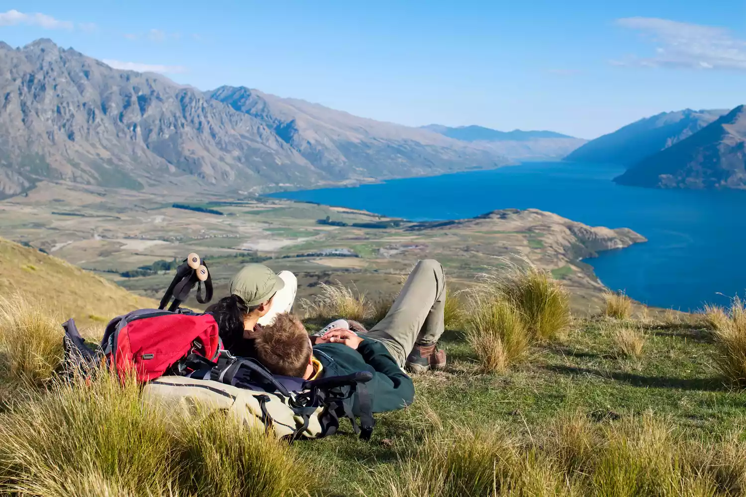 Hikers standing on a mountain ridge overlooking the vast Queenstown landscape