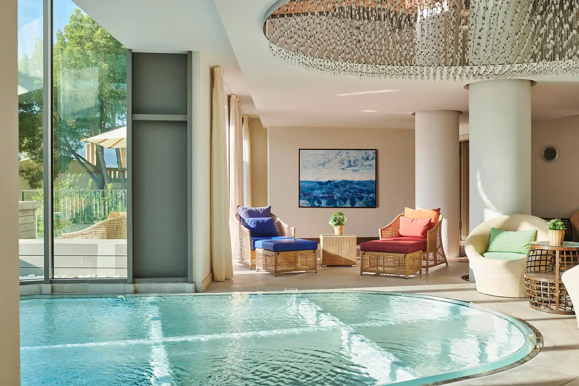 An indoor spa pool with lounge chairs and natural light from large windows.