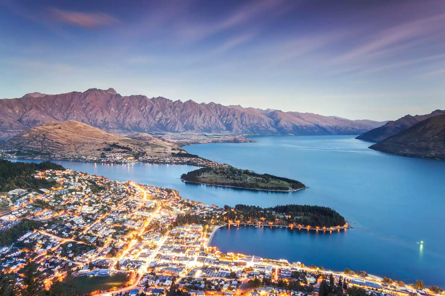 A dusk view of the Queenstown New Zealand skyline against the mountains.
