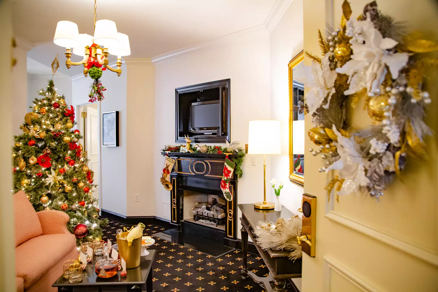 An ornate doorway decorated with a wreath opening into a festively decorated hotel suite.