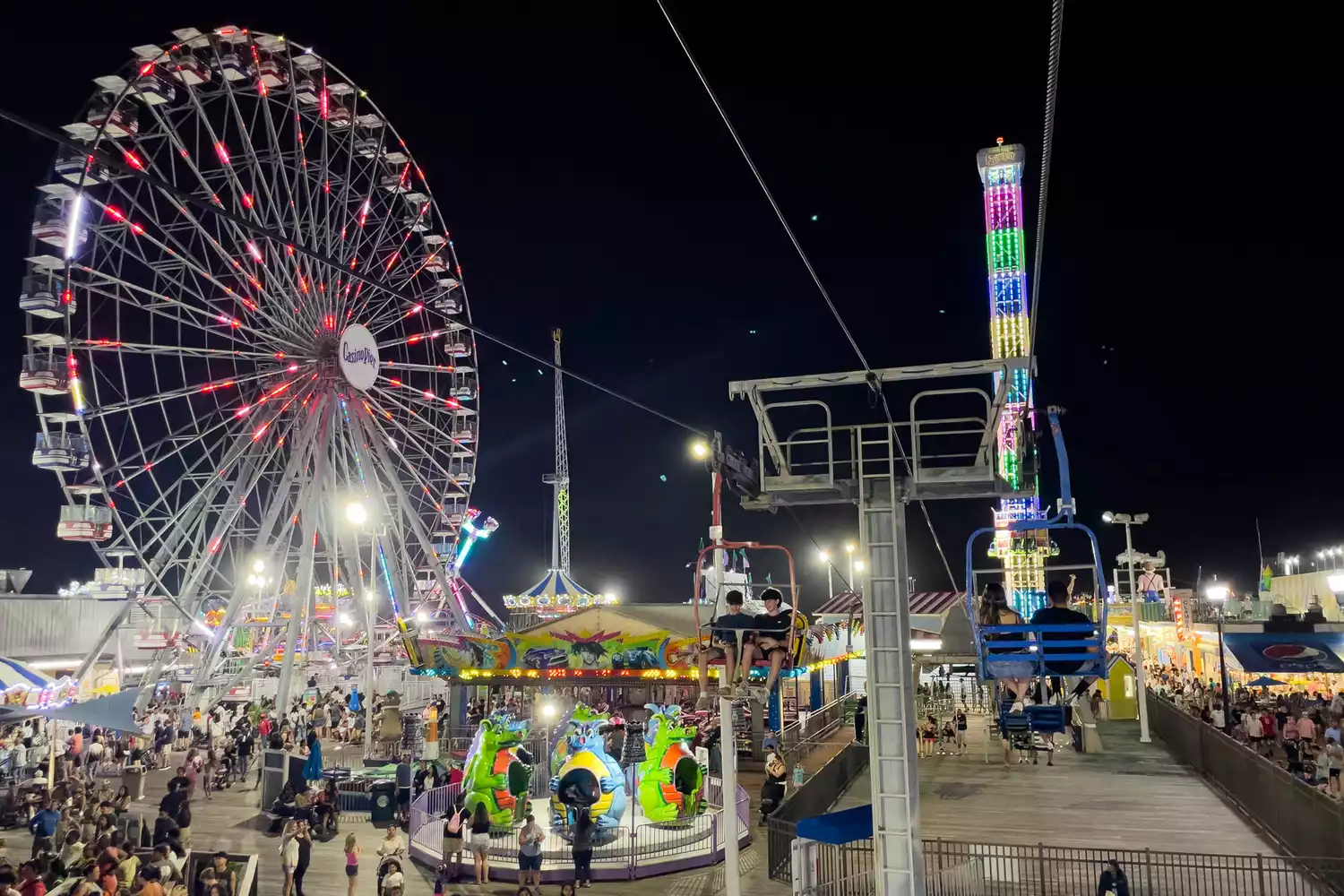 The neon signs and amusement rides of Seaside Heights boardwalk glowing at night.