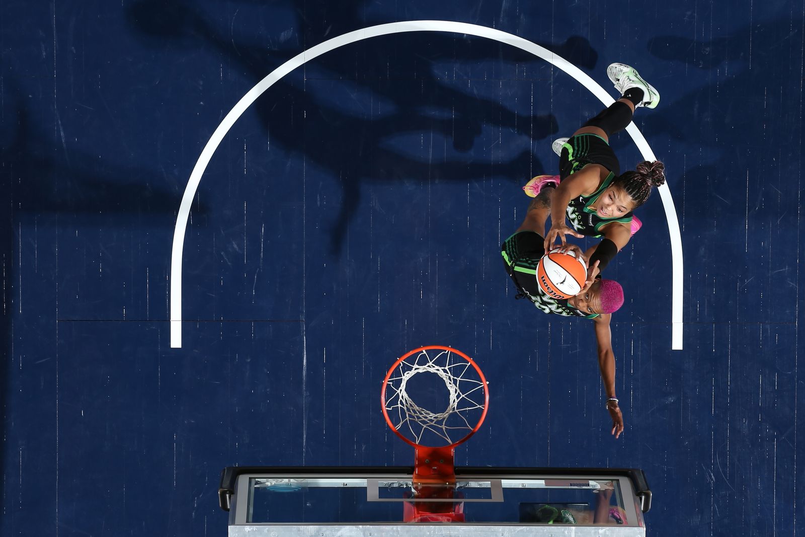 A basketball player in action during a game with a basketball hoop in the background.