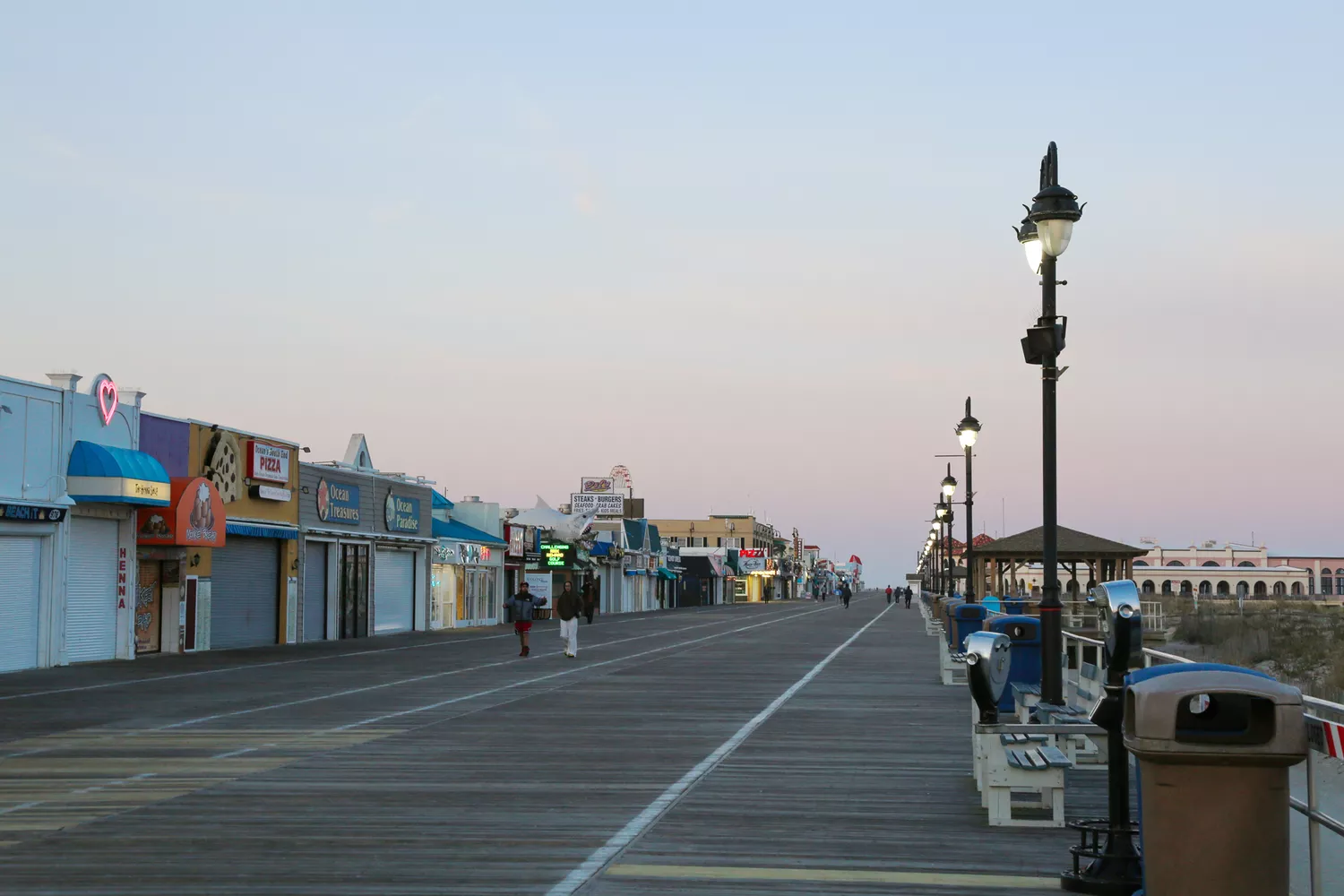 The Ocean City boardwalk at dusk with warm lighting and the silhouette of a Ferris wheel.