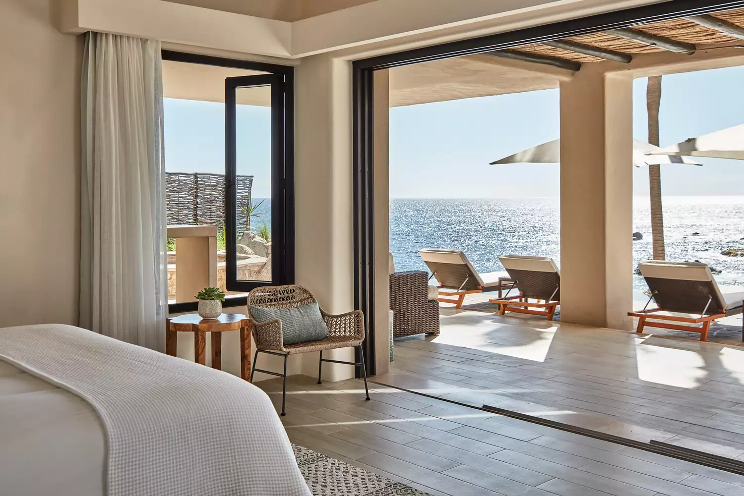Vibrant hotel room interior in Los Cabos featuring a private balcony and views of the azure ocean.