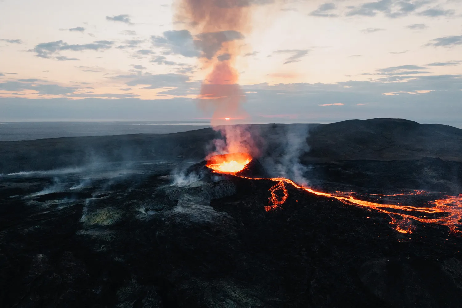 Dramatic view of an active volcanic eruption with glowing lava and rising steam towers.