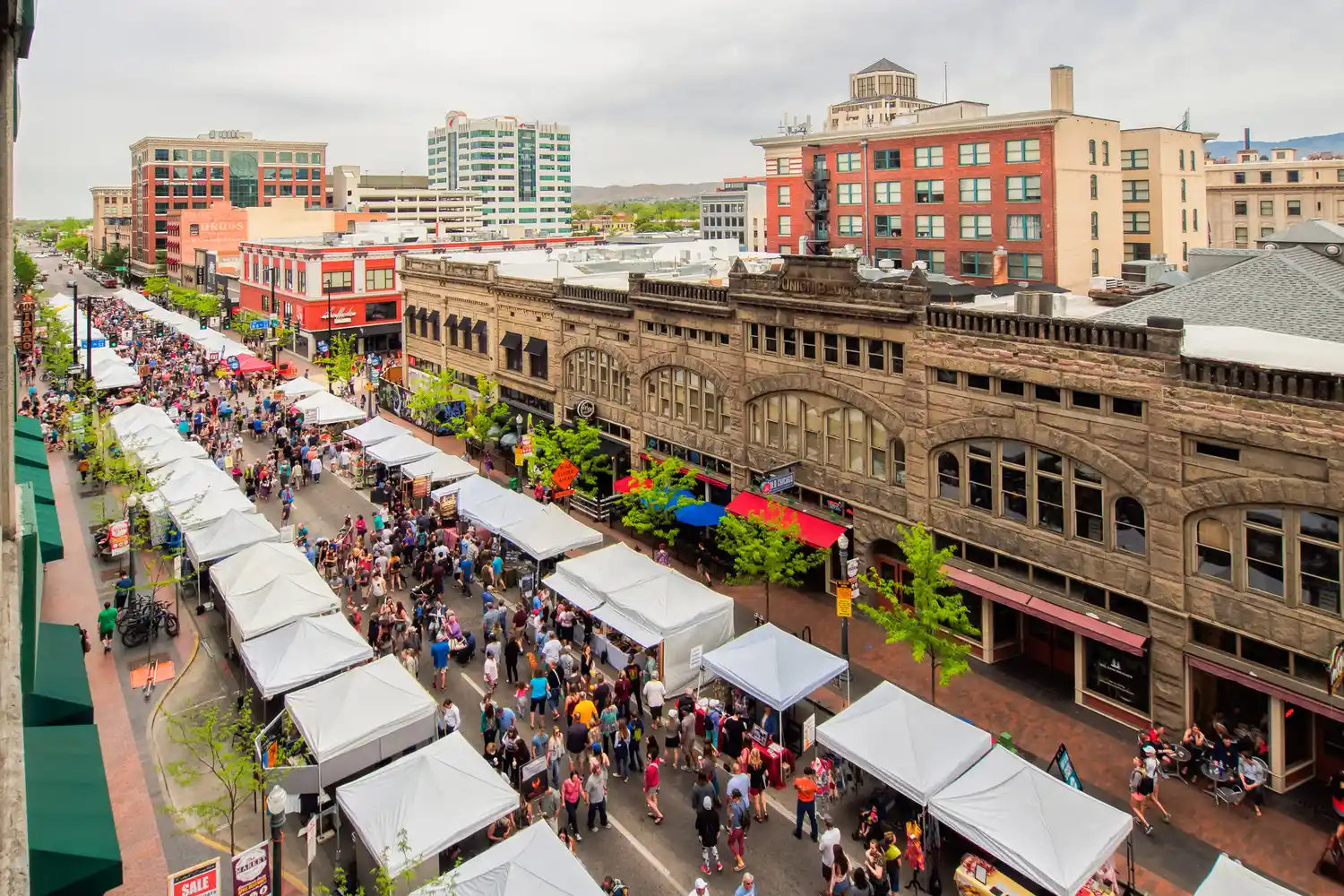 Overhead view of a street market set along a commercial area with multiple vendor booths and a crowd of people