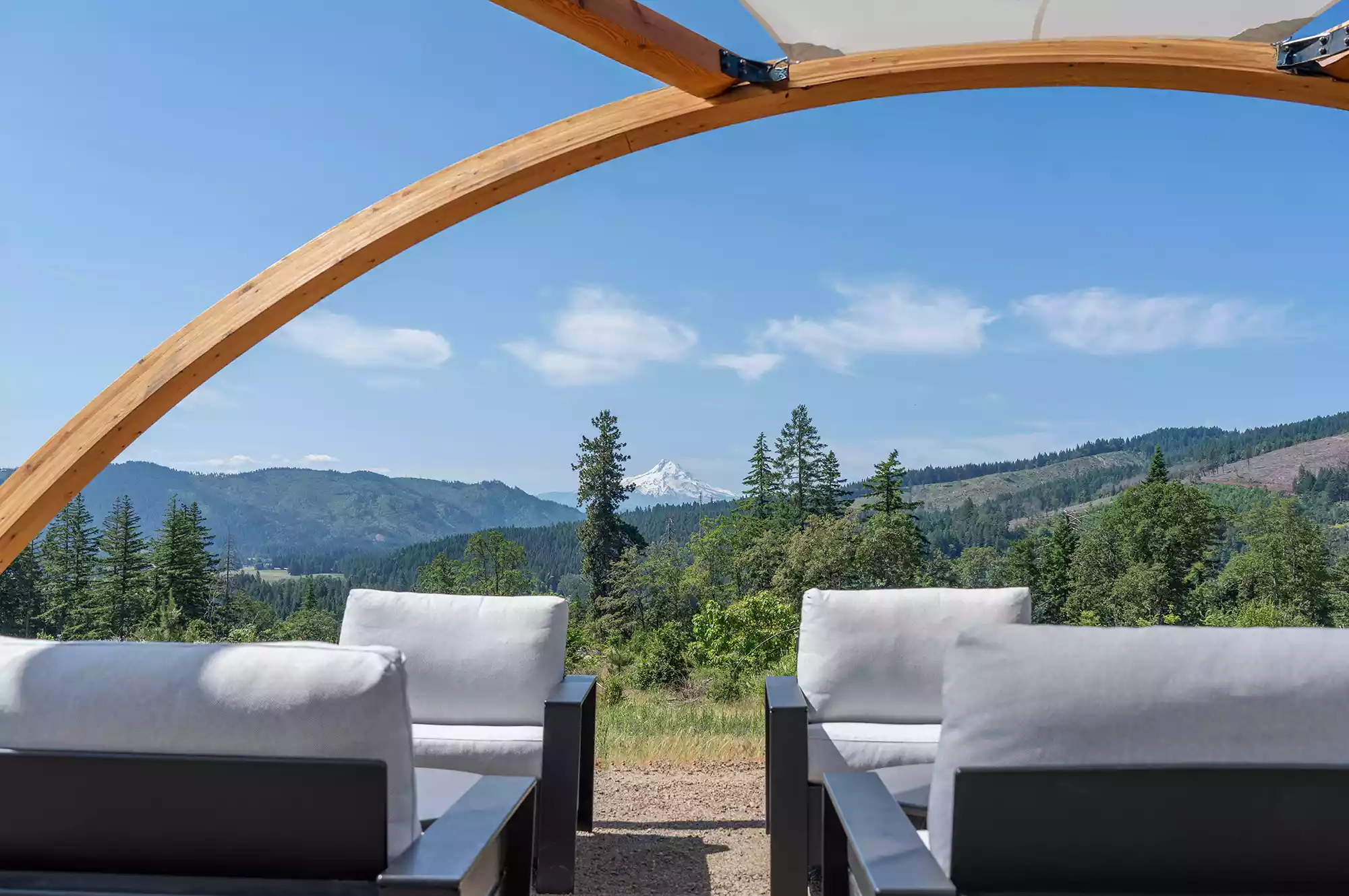 Outdoor wooden archway with lounge chairs looking out over the scenic gorge landscape.