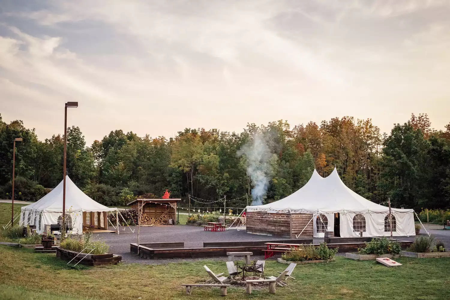 Large white canvas safari tents on raised wooden platforms in a wooded area.