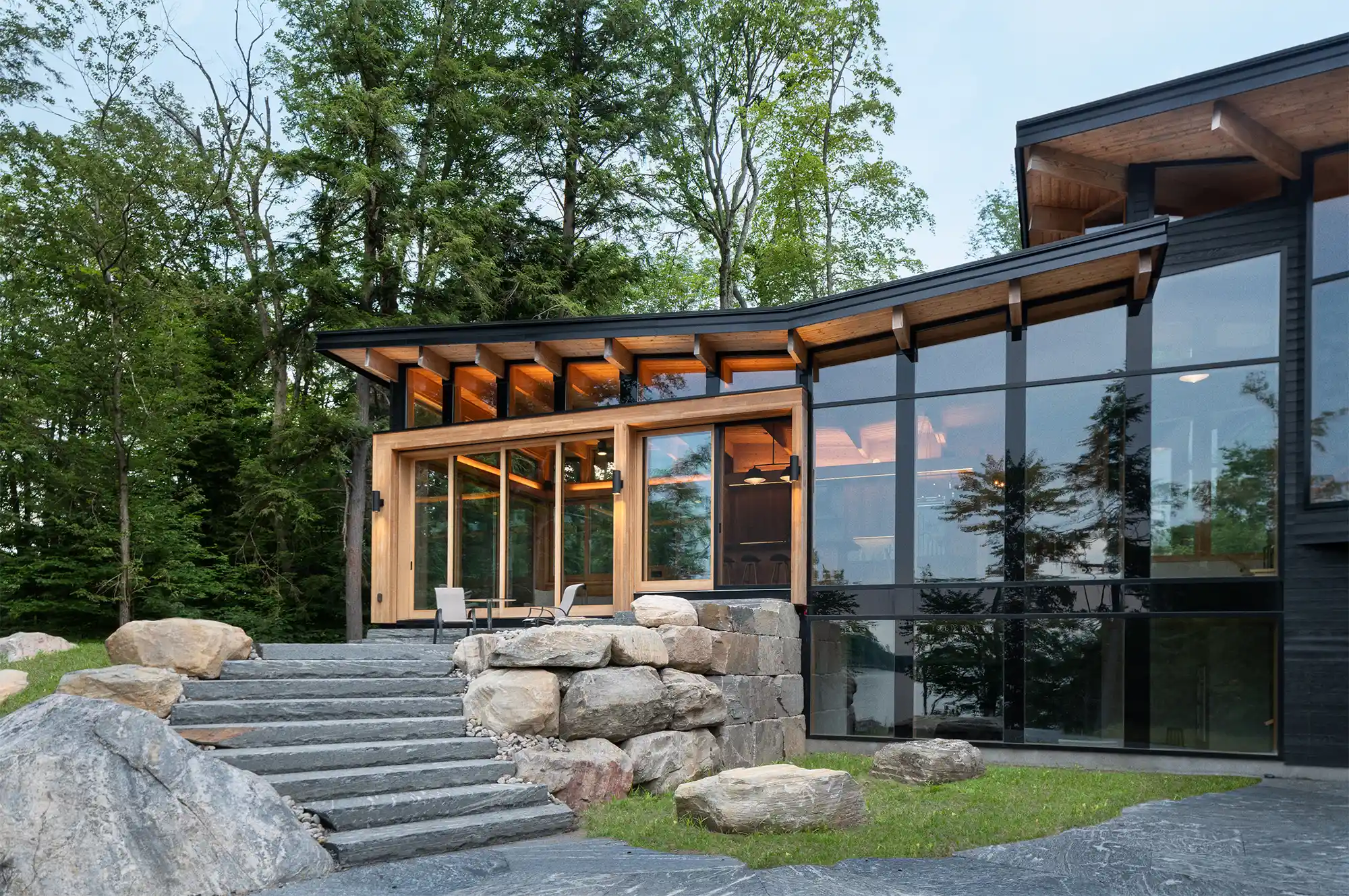 A striking glass and stone facade of the modern Barlochan Cottage with outdoor stone steps.