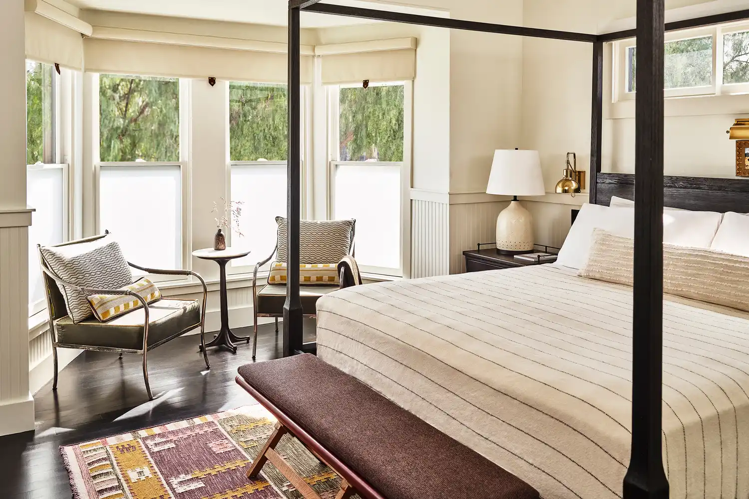 A luxury hotel guest room featuring a four-poster bed and elegant natural wood accents.