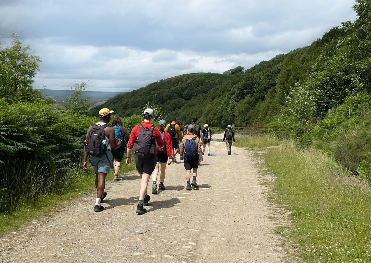 A person equipped with a hiking hat and specialized backpack standing in a natural setting.