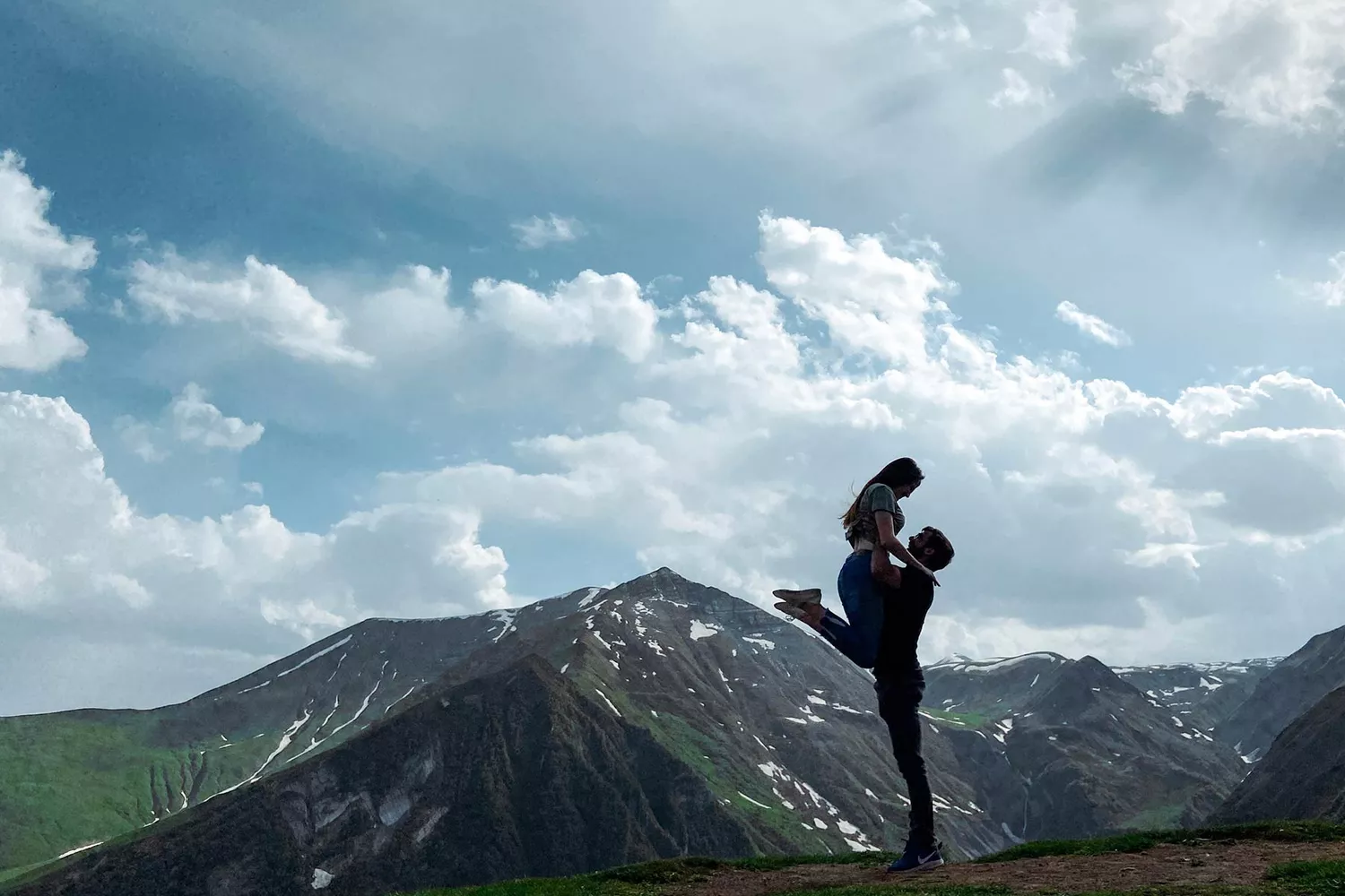 A happy couple performing a dance lift in an outdoor setting in Tbilisi.