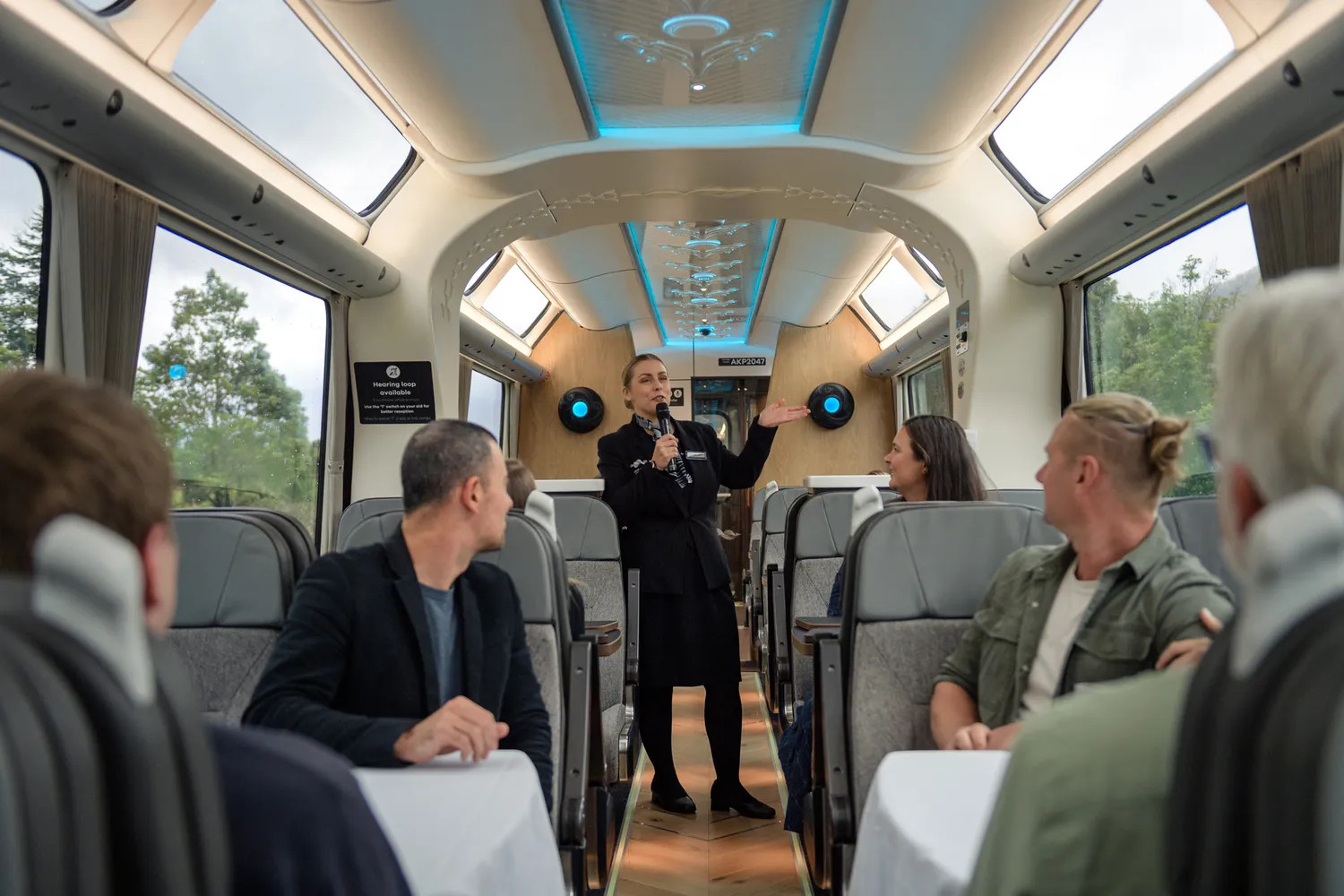 A train attendant assisting passengers in the modern Scenic Plus carriage.
