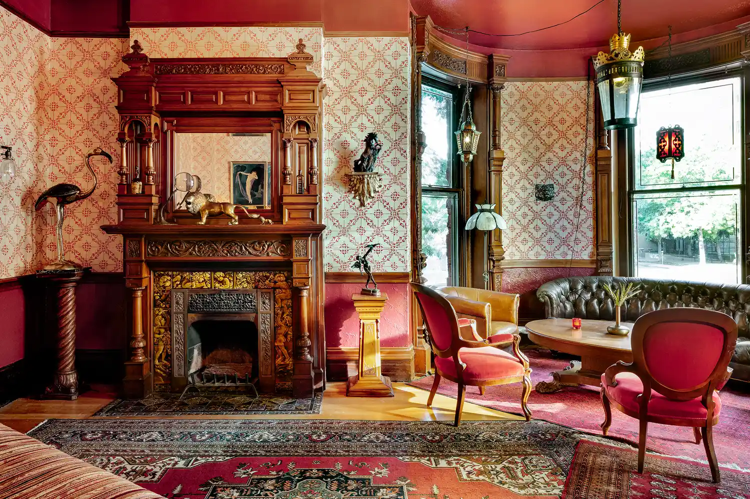 A Victorian-style parlor room with ornate woodwork, a decorative fireplace, and antique furnishings.